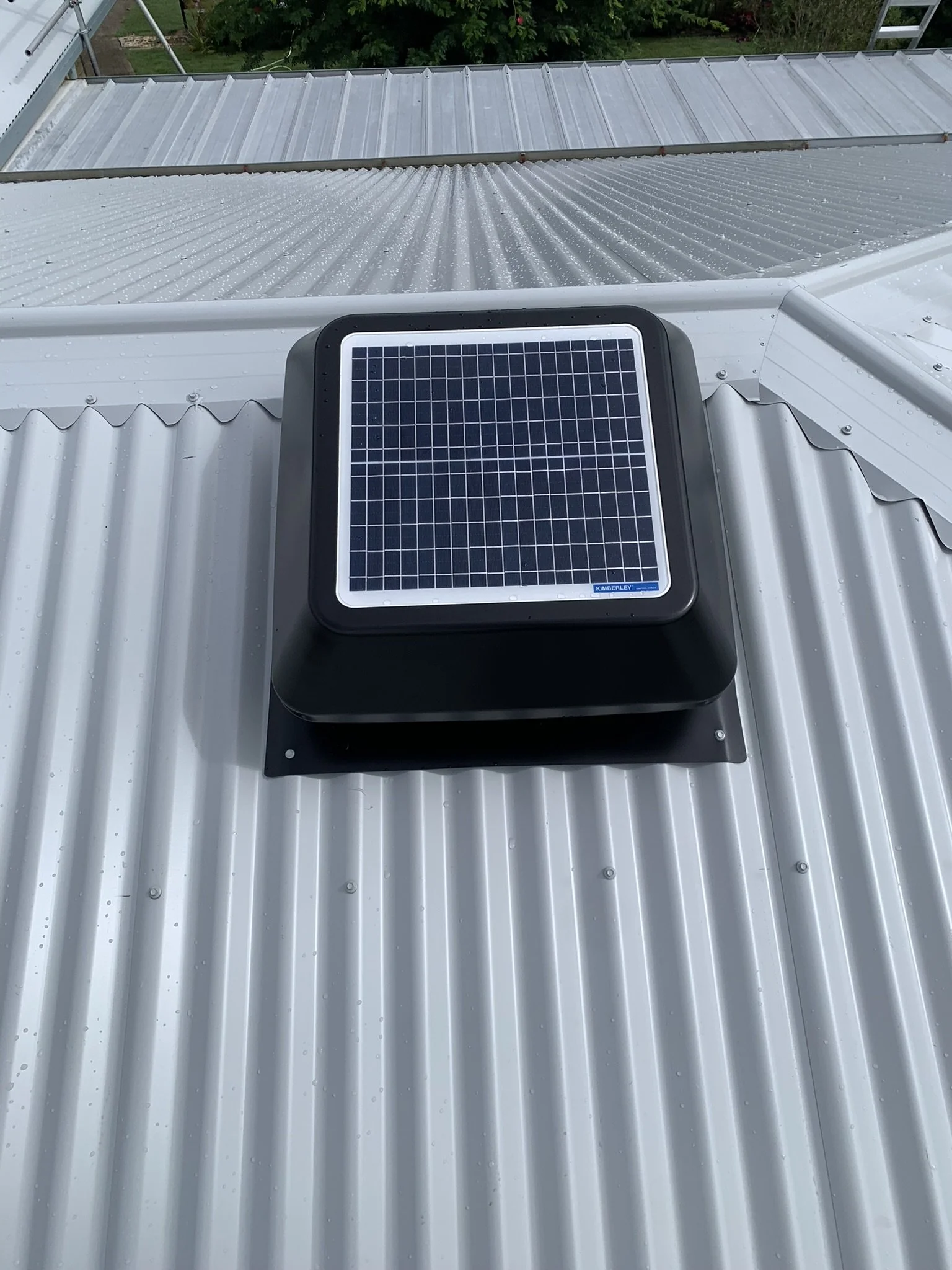 Corrugated metal roof with a solar panel-powered vent.