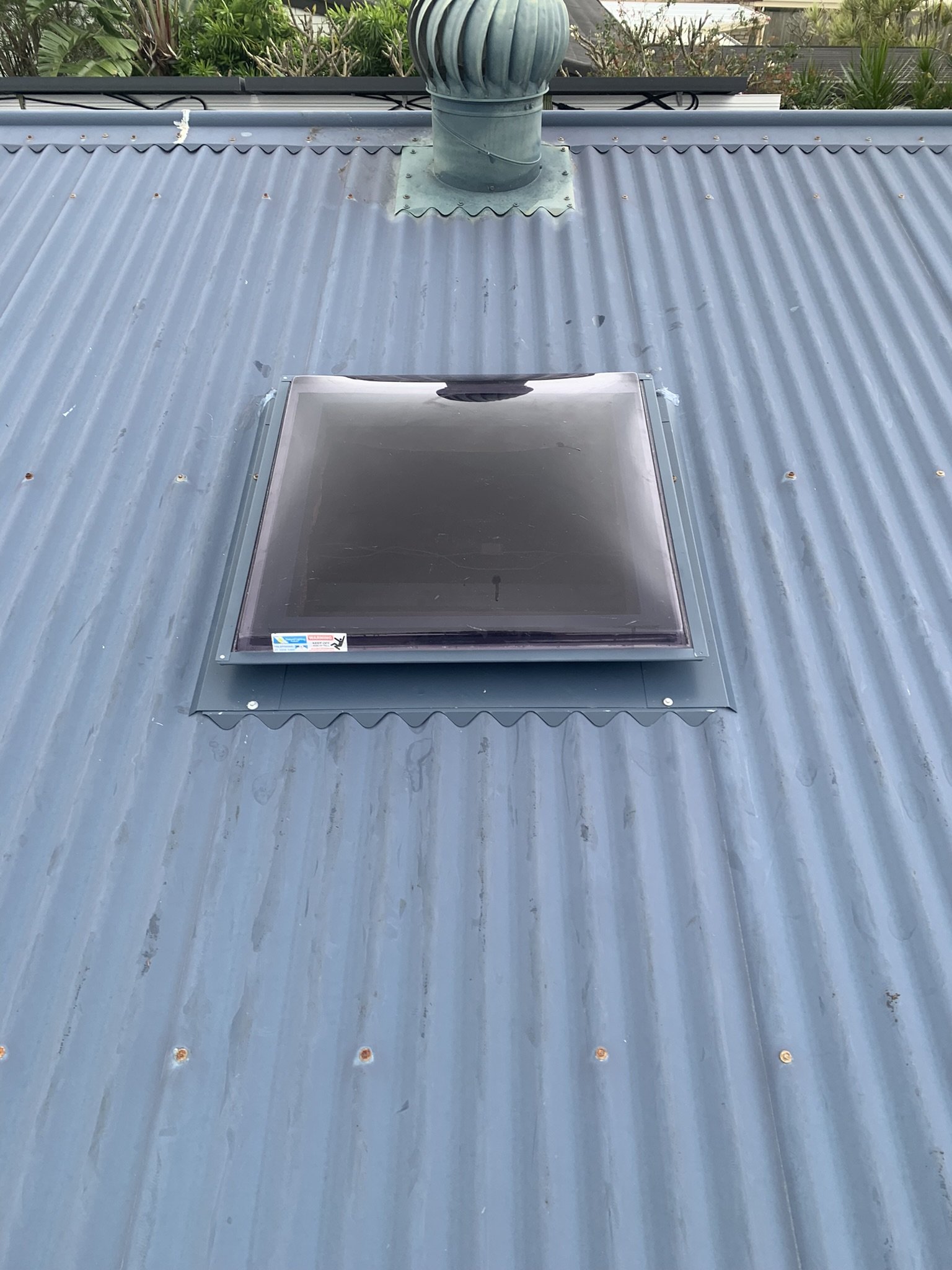 Corrugated metal roof with a skylight and a roof vent.