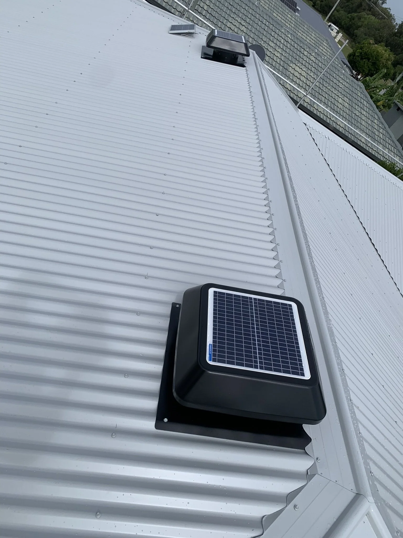 Corrugated metal roof with solar-powered ventilation units.