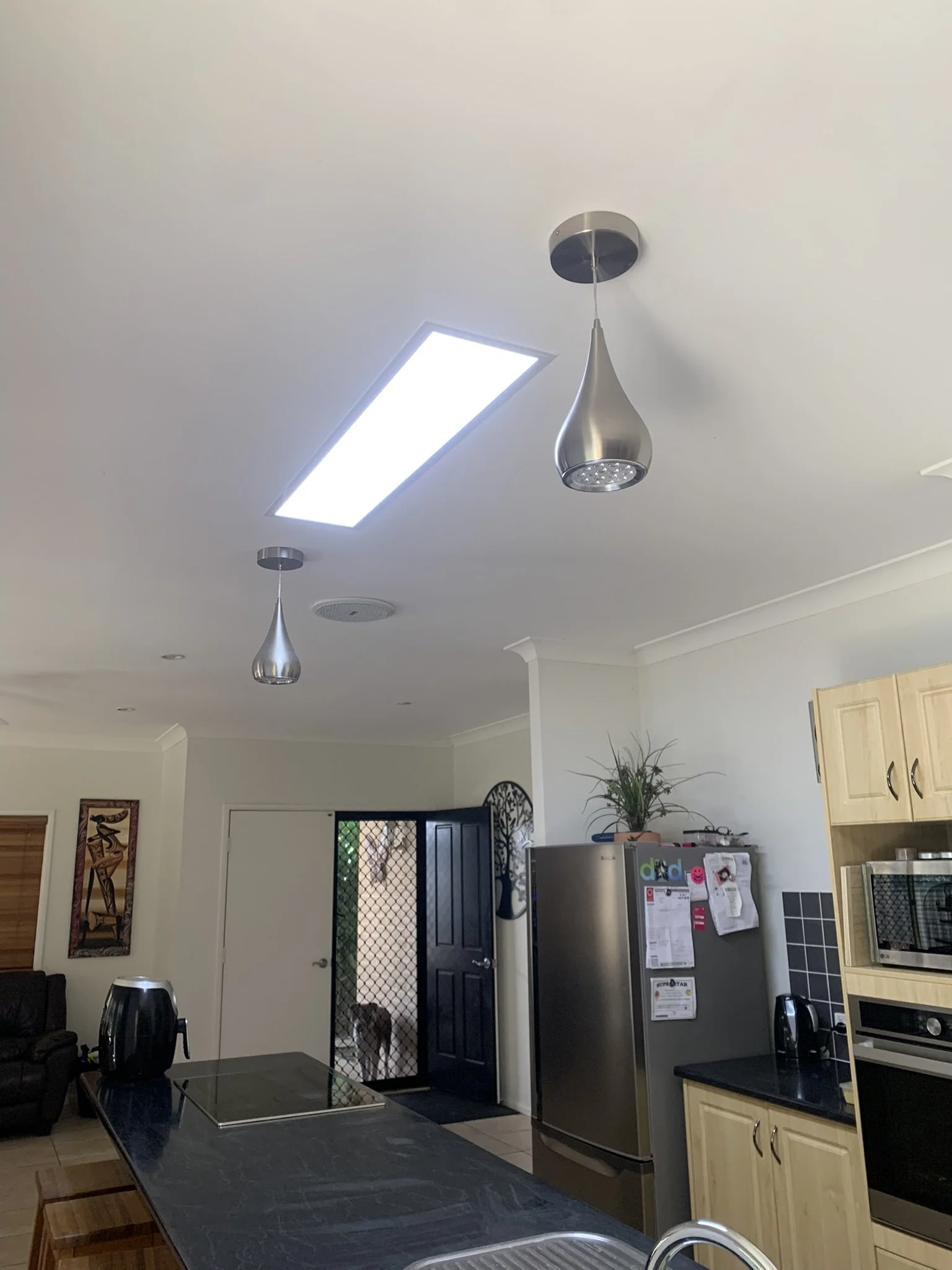 Modern kitchen with pendant lights, refrigerator, appliances and an illume skylight.