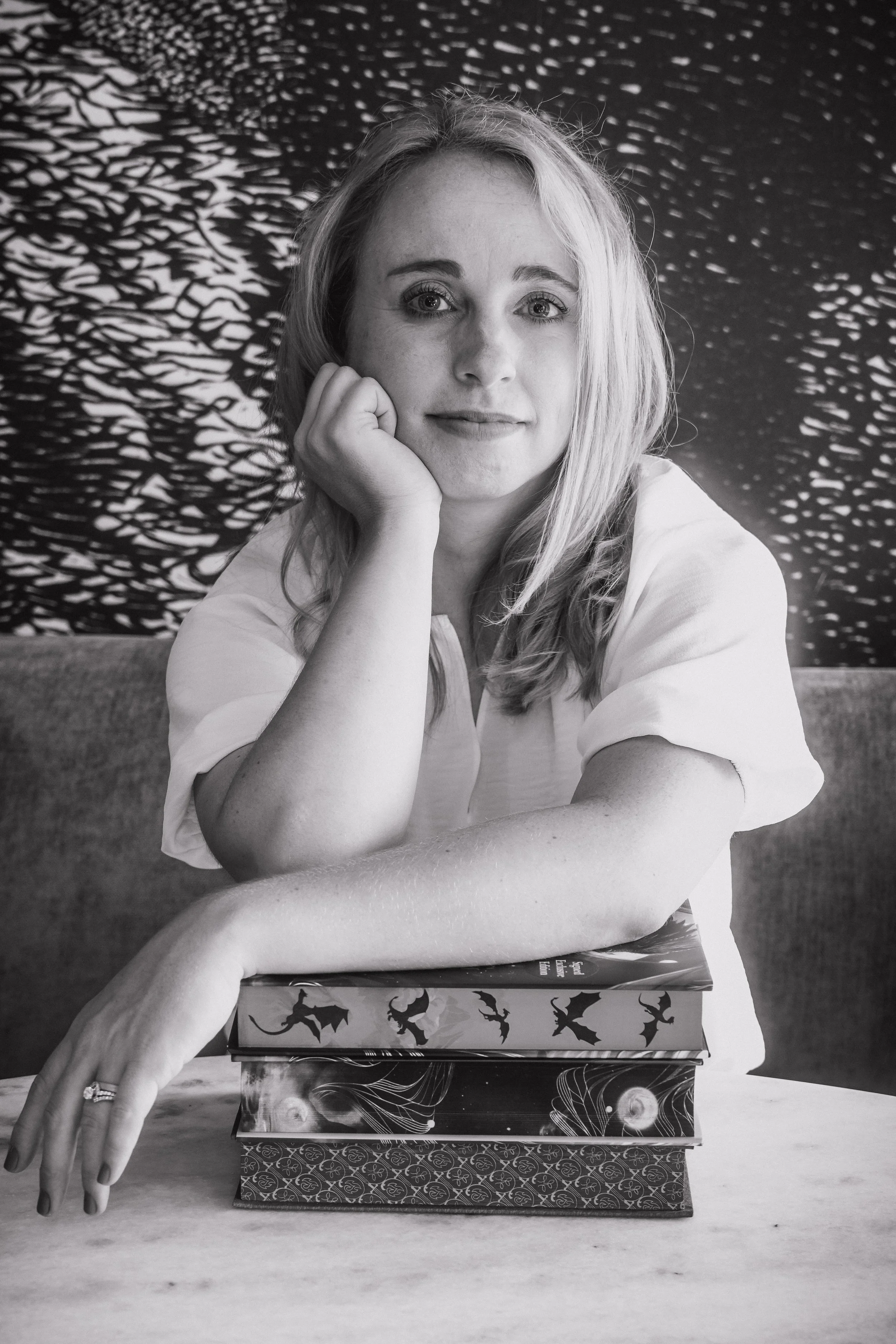 author leaning on books with sprayed edges