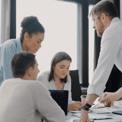 Five professionals engaged in a discussion around a table in a modern office.