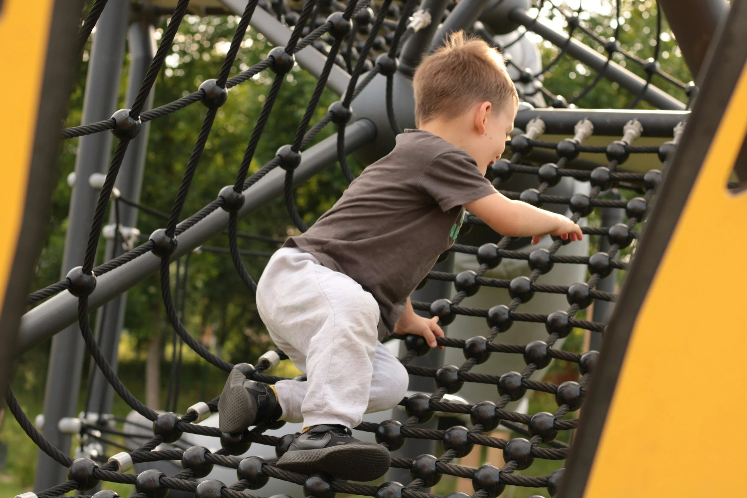 Little boy climbing rope ladder. Large motor activities that help children with autism increase focus. A parent guide.