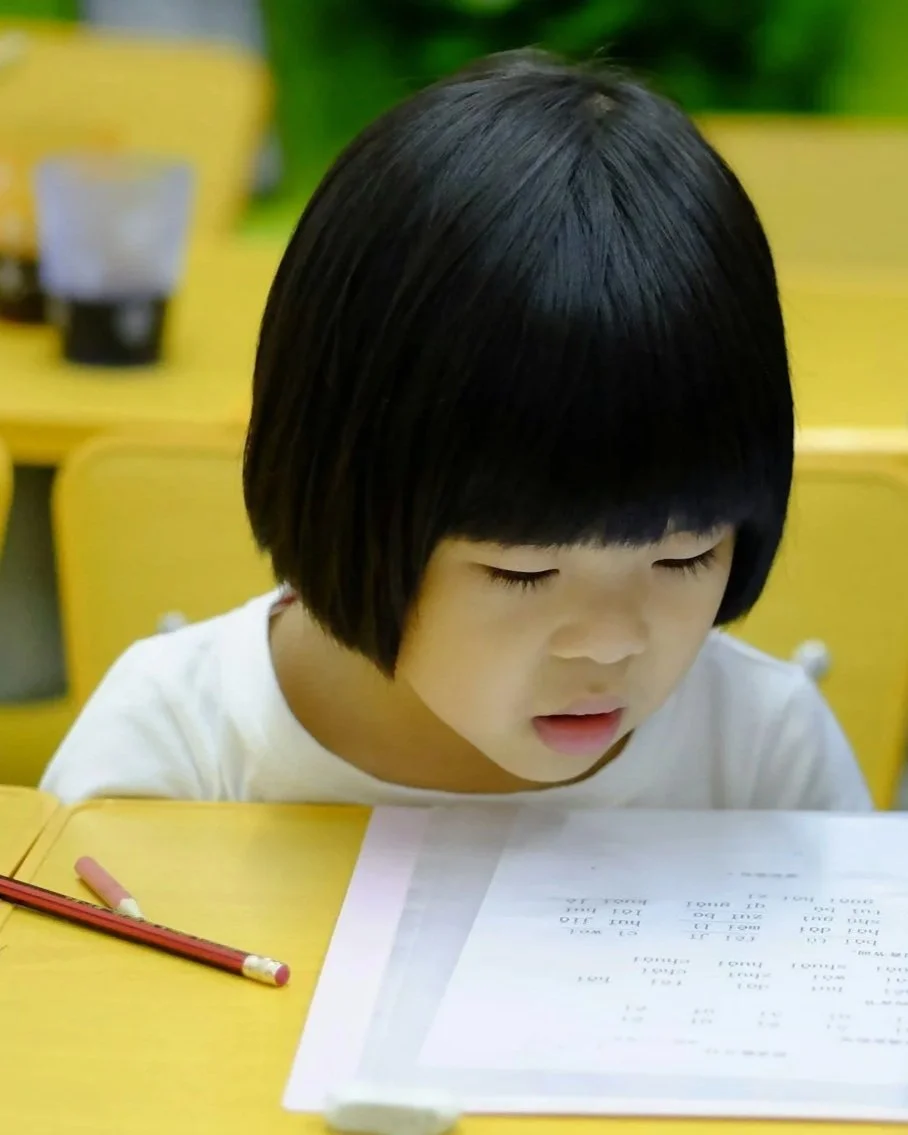 A little girl is taking an academic test with her pencil nearby on the desk. She is thinking hard.