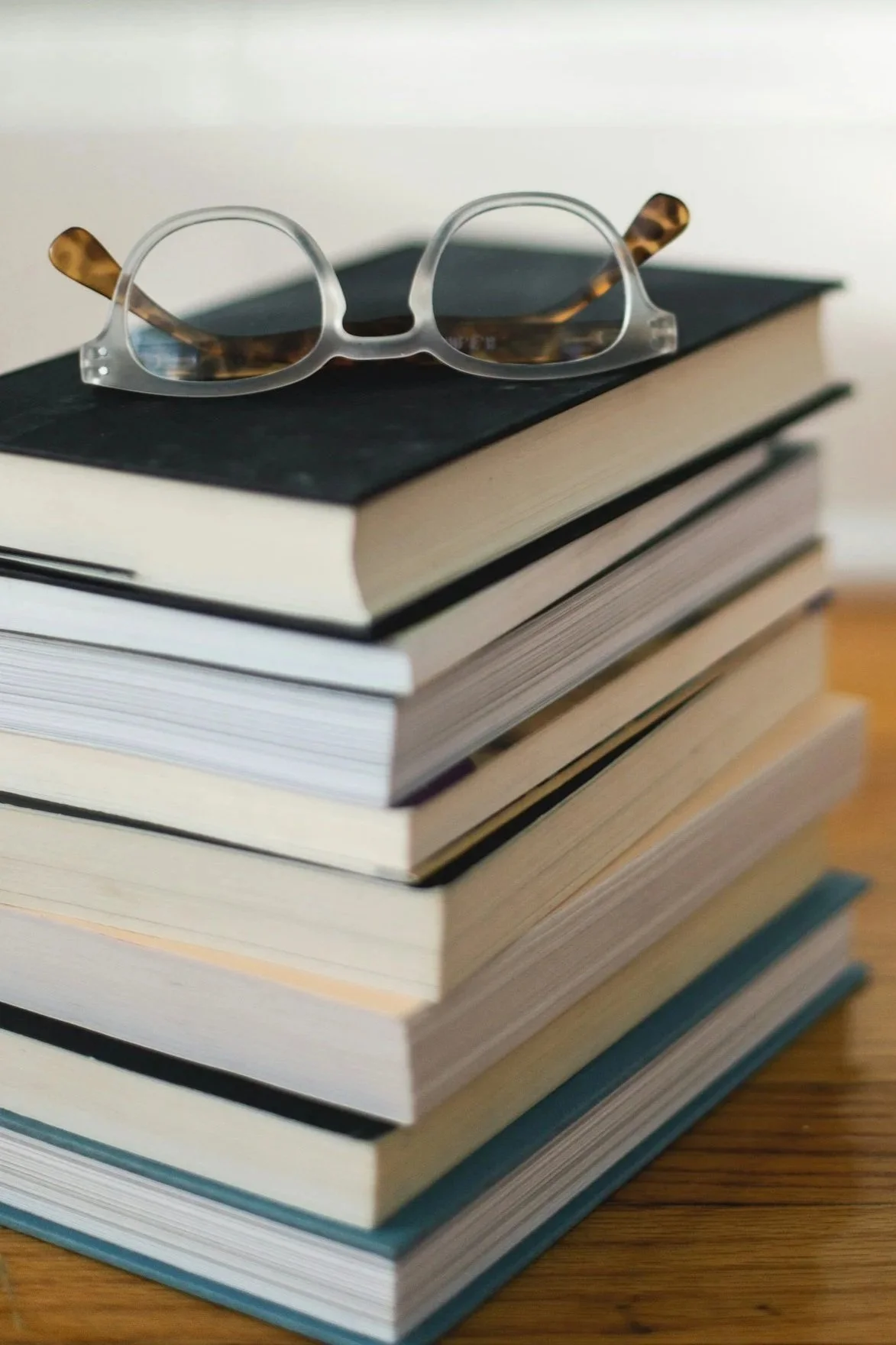 Stack of books and reading glasses. Recommended reading list to guide parents new to homeschooling. Includes books and website free resources.