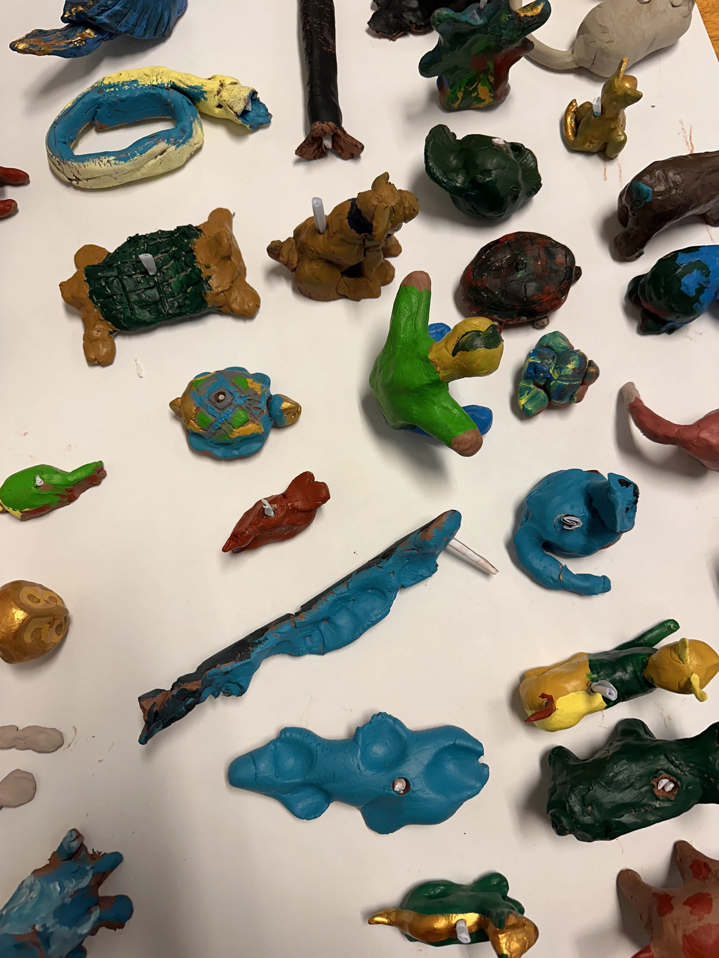 Fargerike, håndlagde figurer av leire plassert på en hvit overflate.