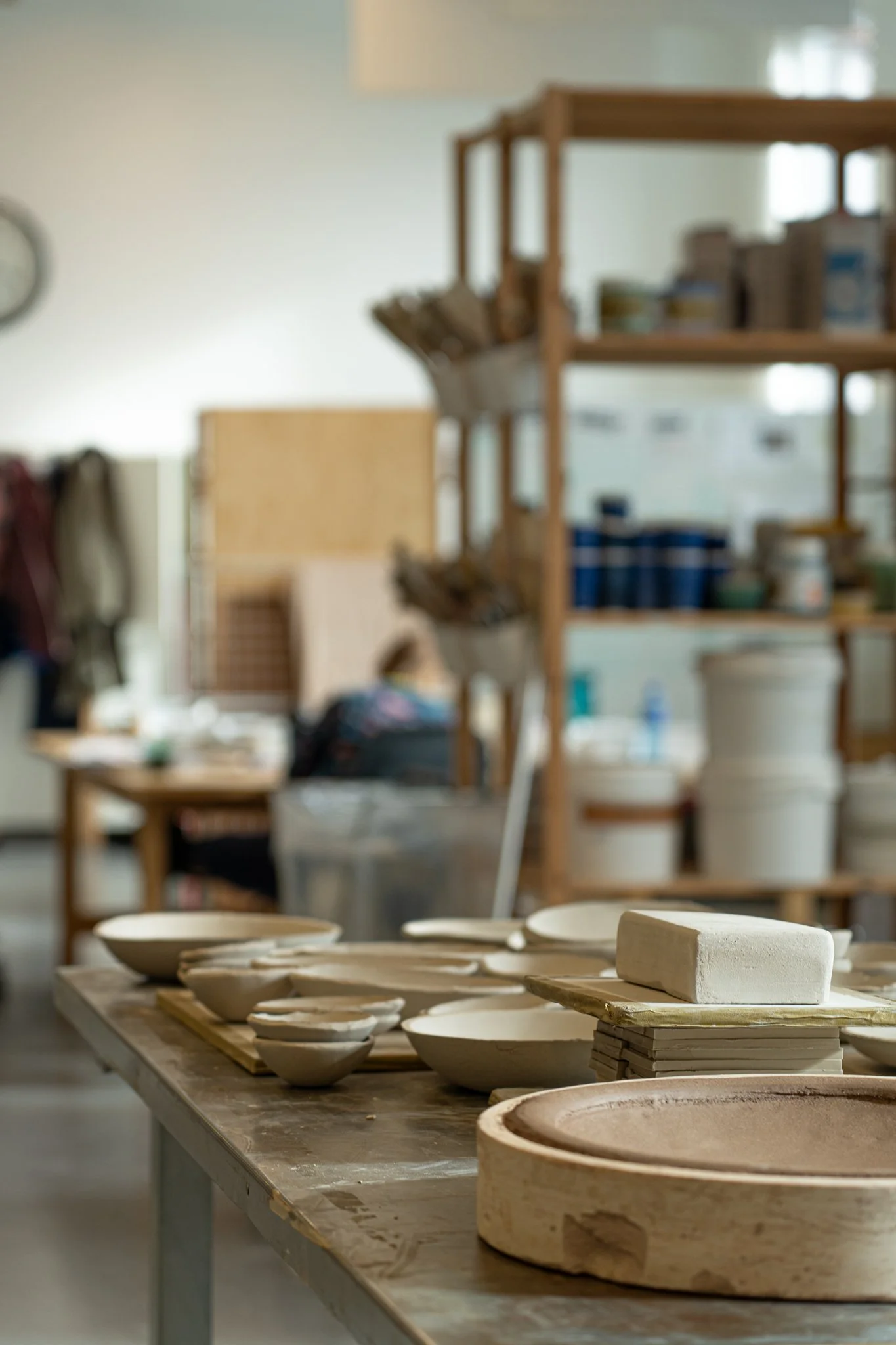 Keramikkfat og former, og en blokk av keramisk leire på en arbeidsbenk