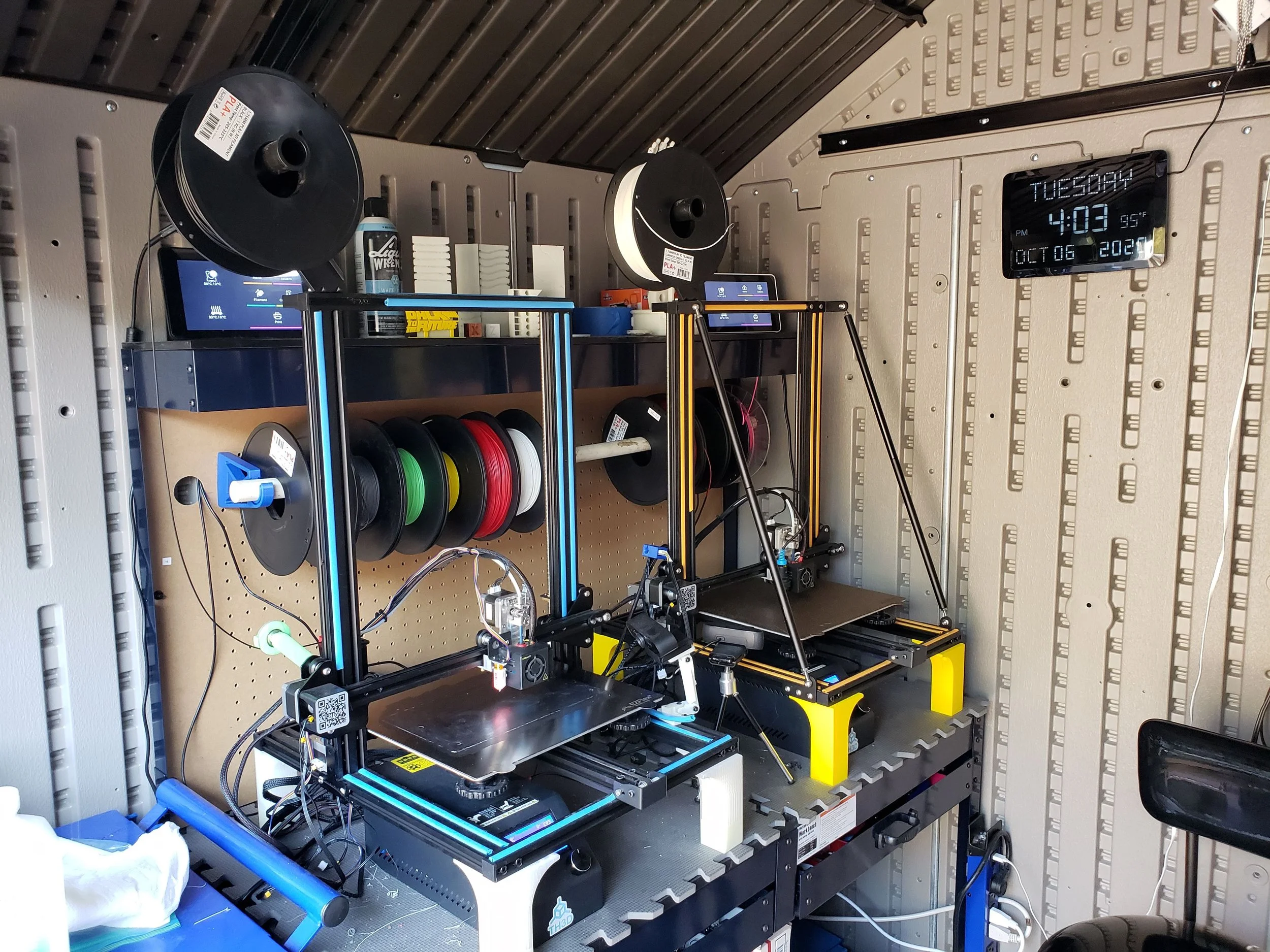 3D printers setup with filament spools and digital clock in a workshop