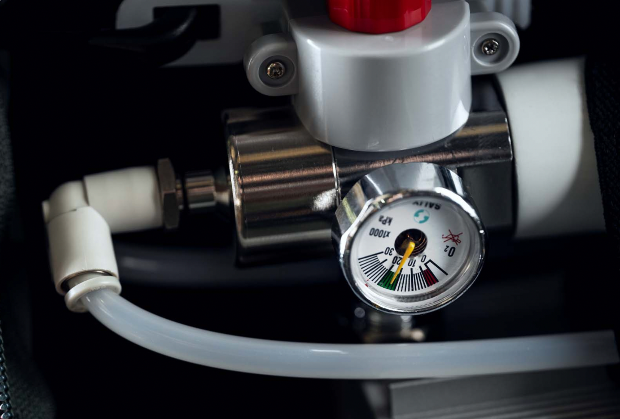 Close-up of an oxygen pressure gauge with connected hoses.
