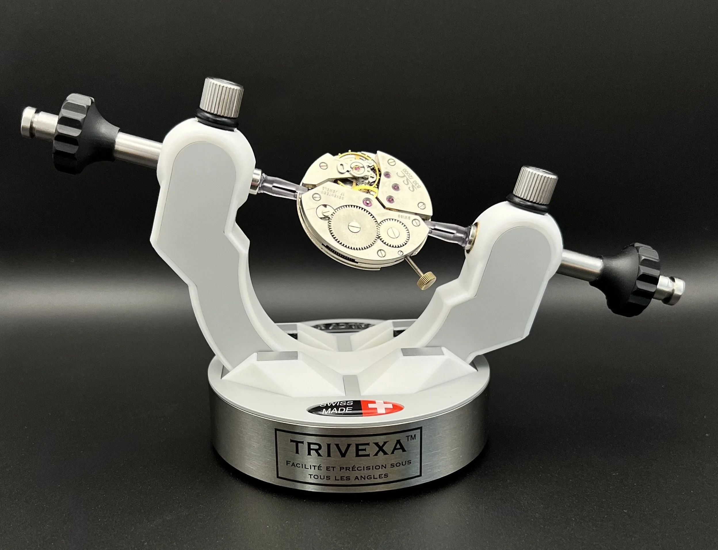 Support d'horlogerie Trivexa avec mécanisme de montre fixé, fond noir.