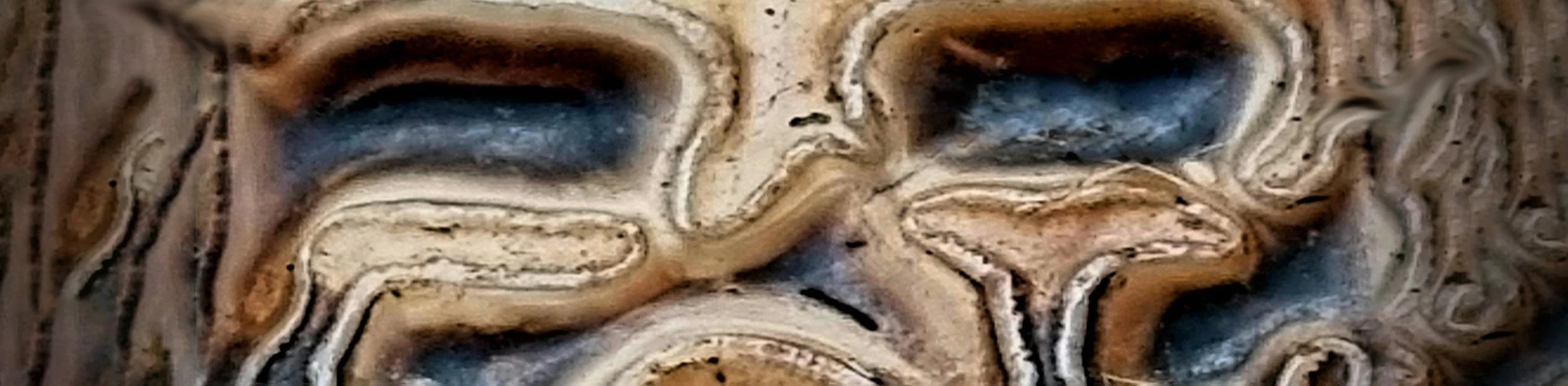 En träskulptur föreställande ett människohuvud, snidad ur ett stycke trä med tydliga årslager och textur.