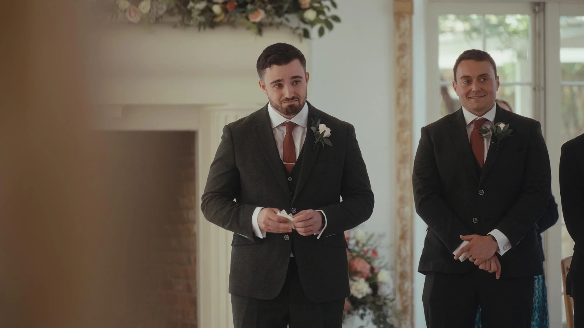 A groom emotionally watching his bride walk up the aisle during their wedding ceremony.