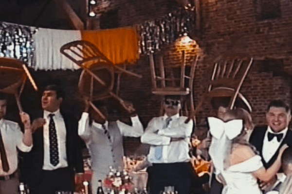 A VHS clip of people at a party holding chairs above their heads