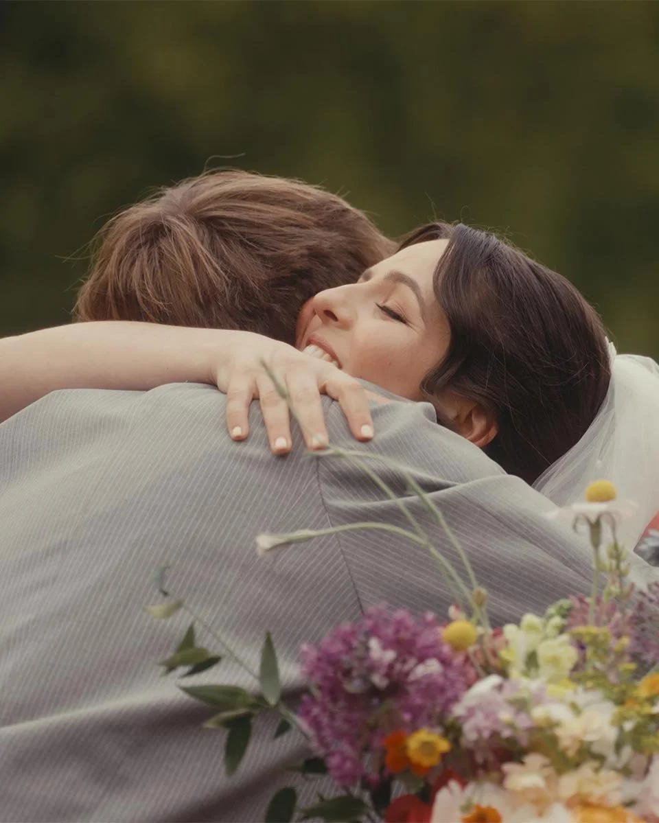 A woman and a man embracing in a hug outdoors.