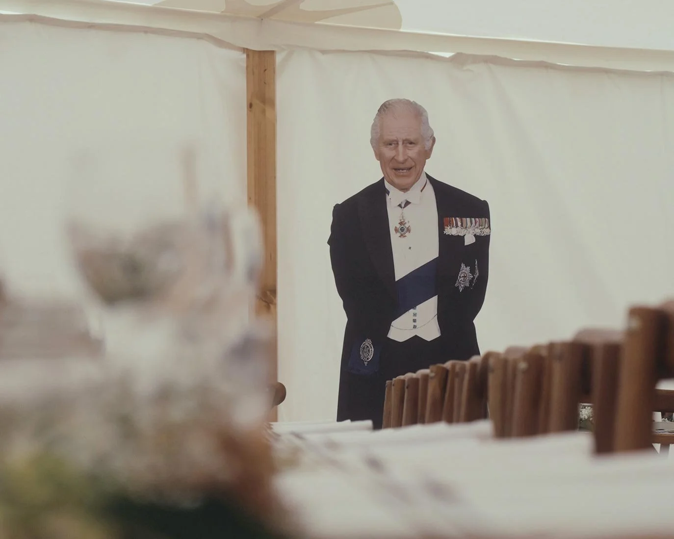 Large cardboard cutout of King Charles in a marquee setting.