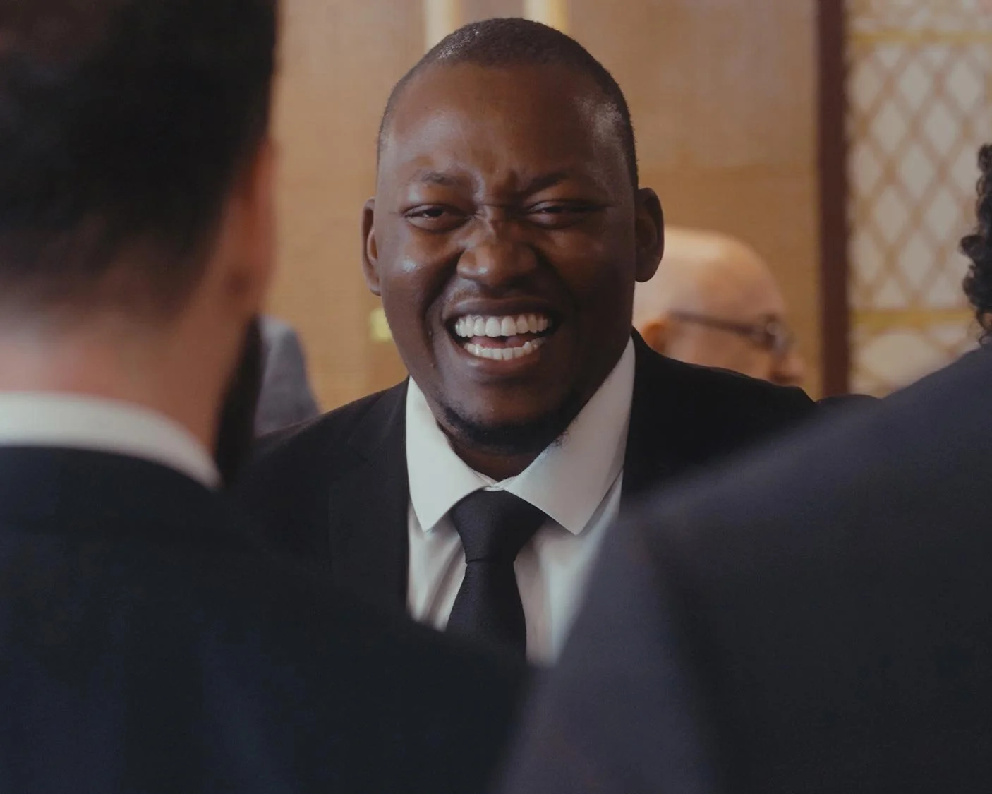 Man in a suit laughing in a social gathering
