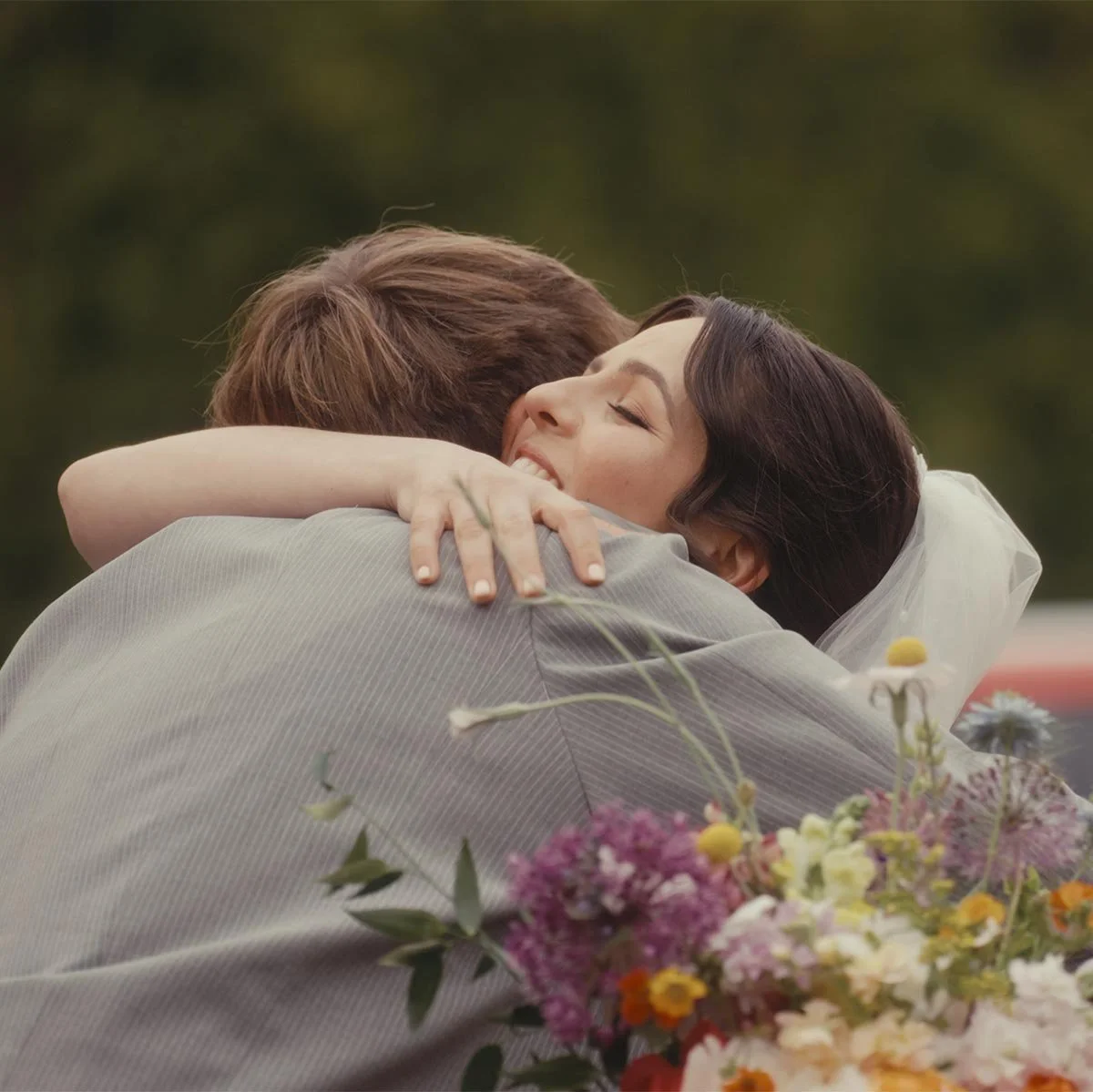A woman and a man embracing in a hug outdoors.