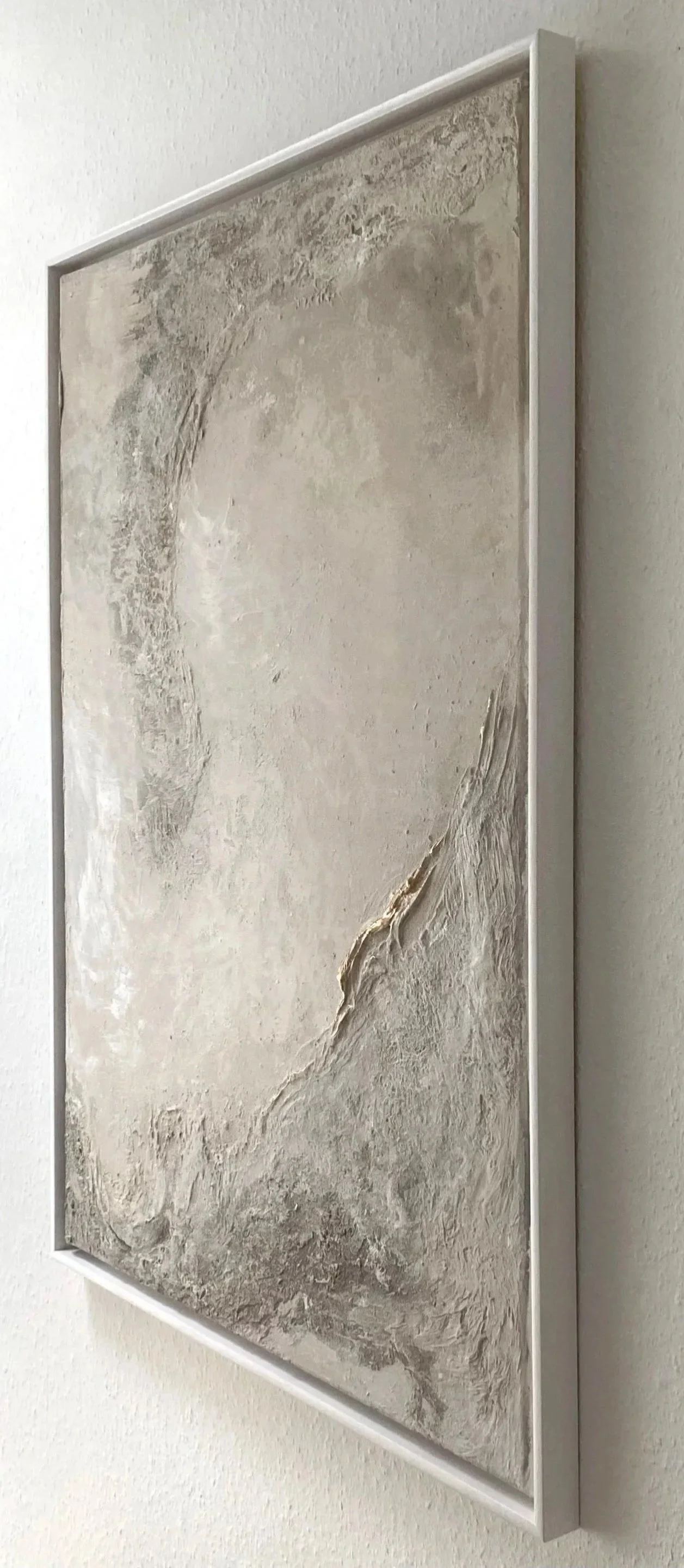 Abstraktes Bild in neutralen Tönen, gerahmt, an einer weißen Wand.