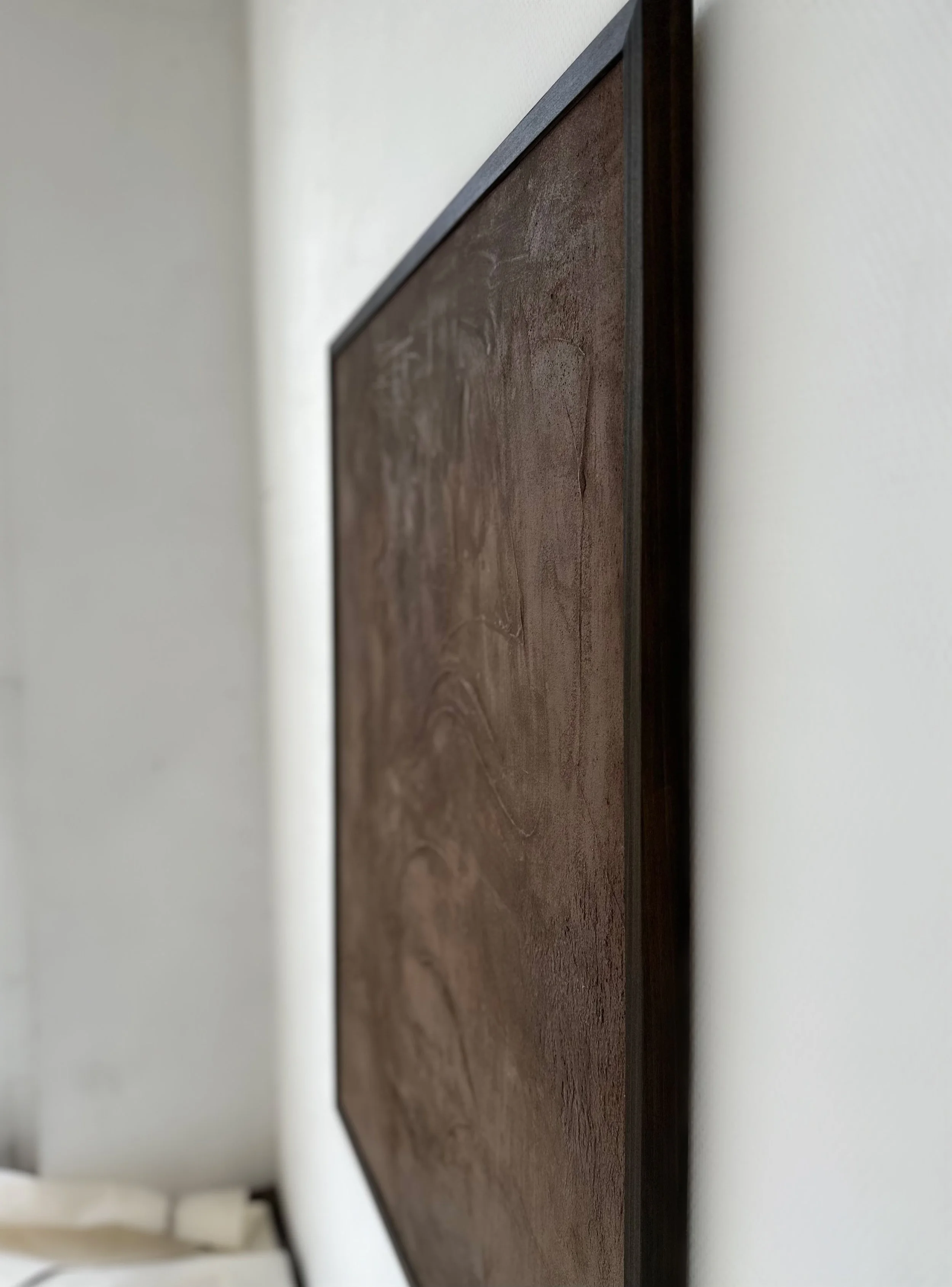 Ein seitlicher Blick auf ein Wandbild mit Holzmaserung, das an einer weißen Wand hängt.