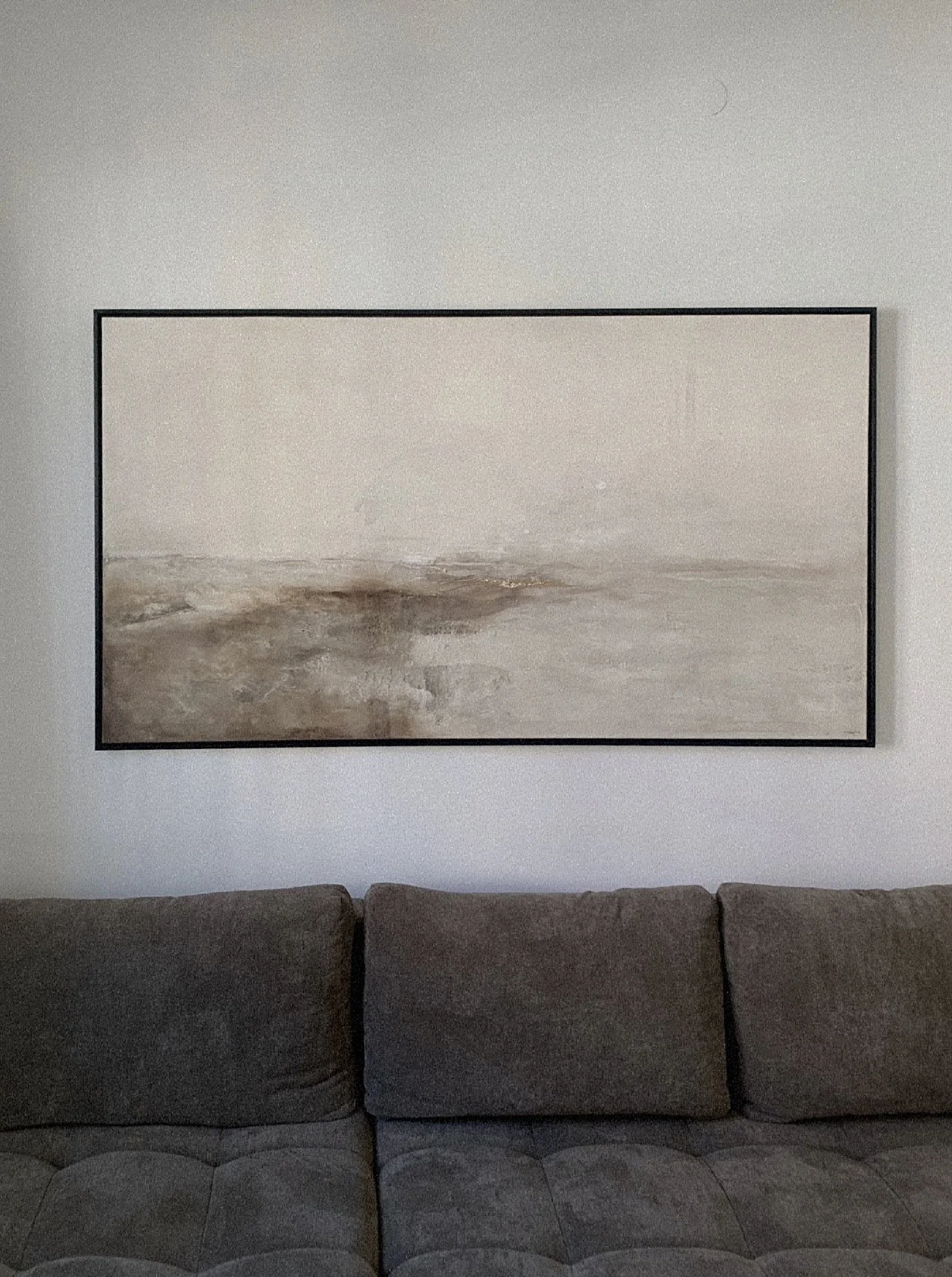 Ein Wohnzimmer mit einer Couch und einem großformatigen abstrakten Gemälde an der Wand.