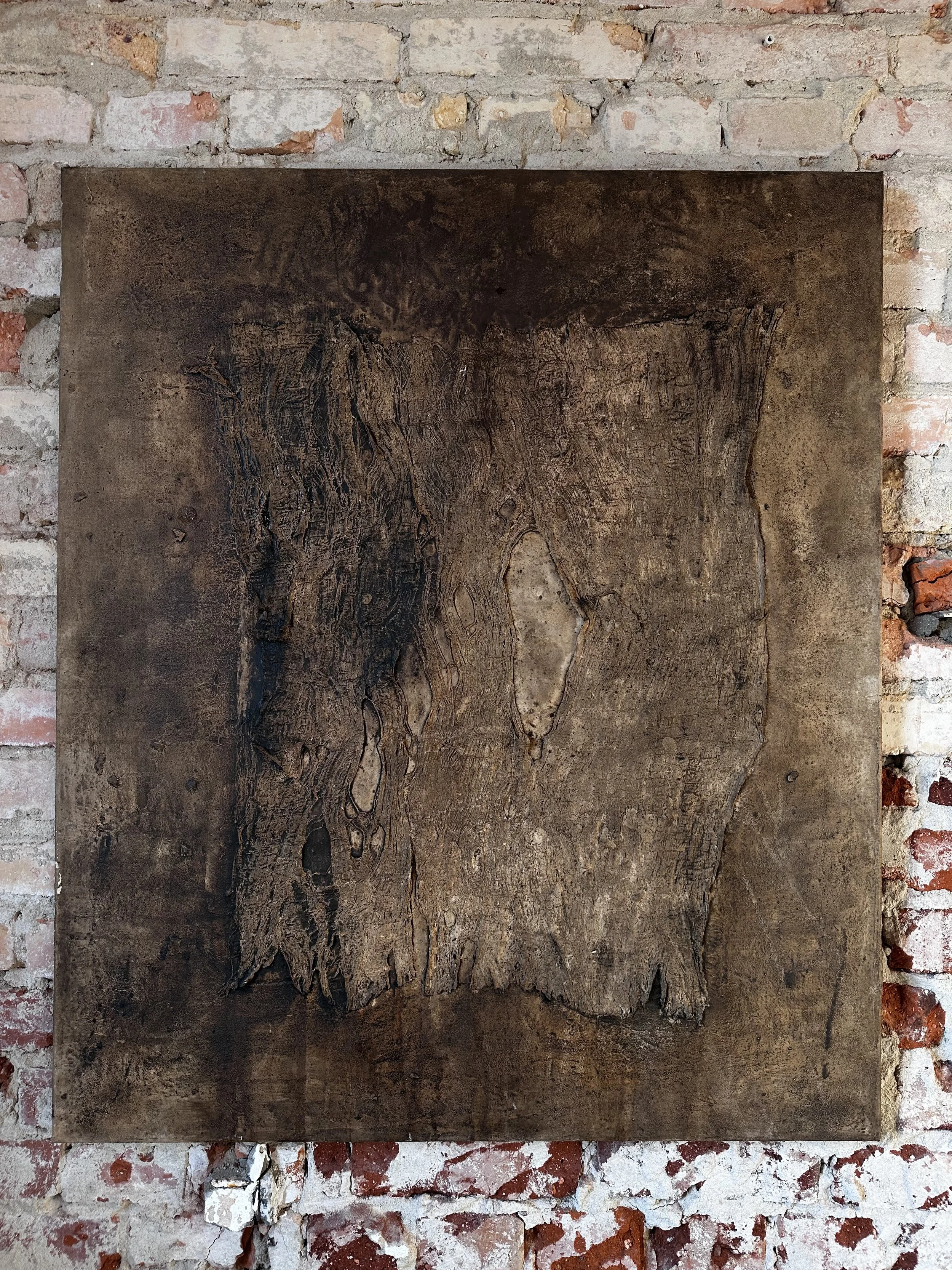 Ein altes, verwittertes Holzstück vor einer Backsteinmauer.