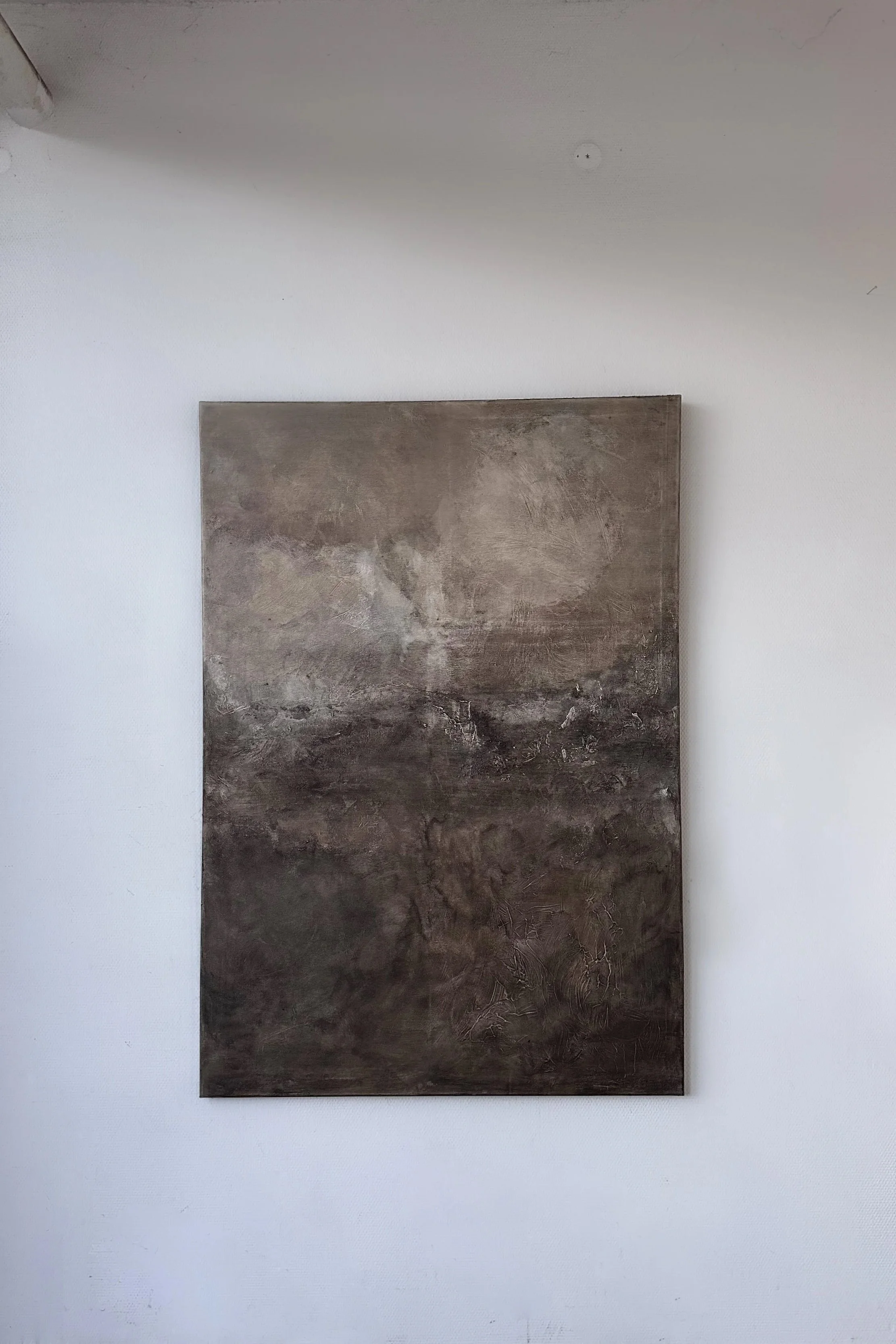 Ein großes, abstraktes Gemälde in dunklen, erdigen Tönen an einer weißen Wand.