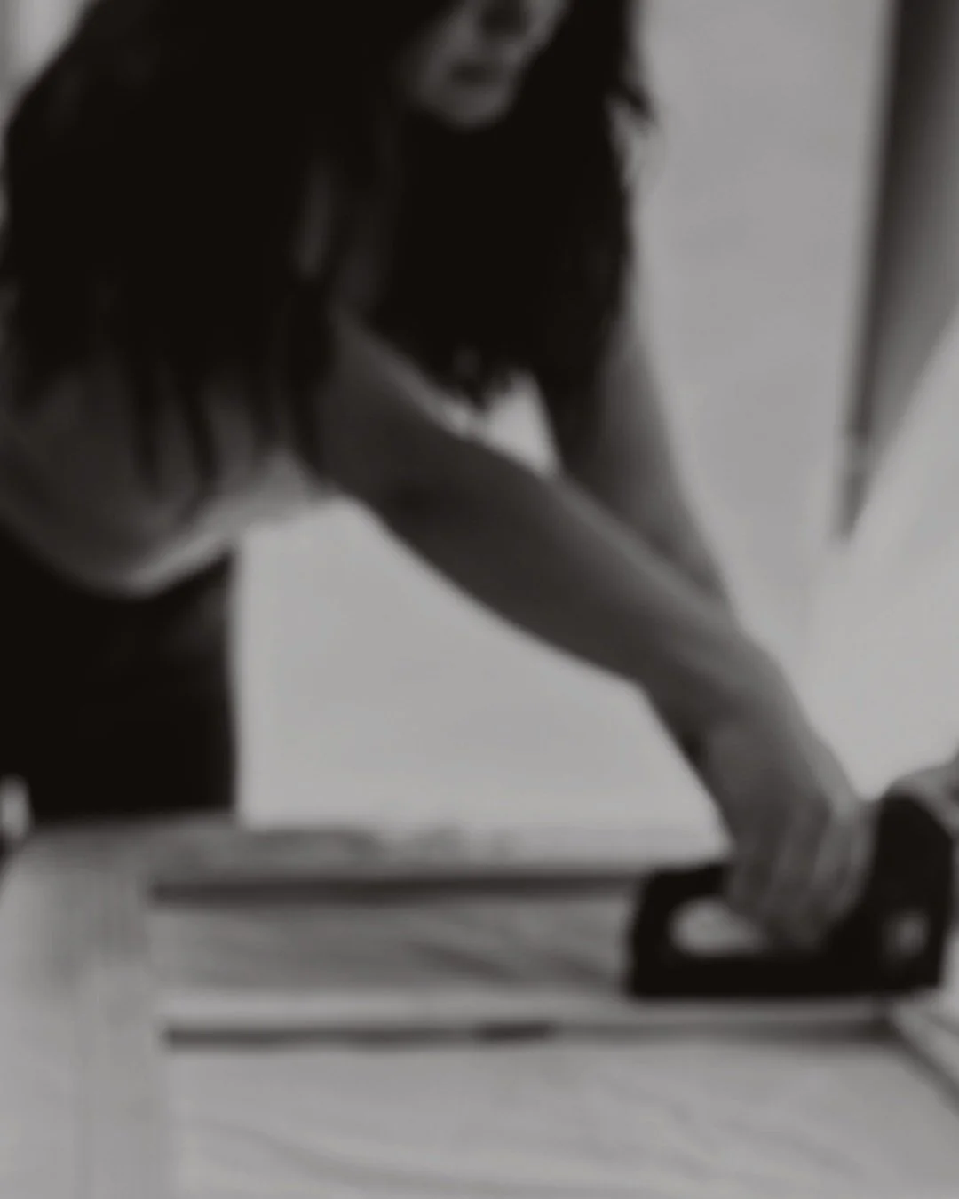 Eine Frau sitzt auf einem Tisch, die Perspektive ist schräg von unten, das Bild ist schwarz-weiß und unscharf.