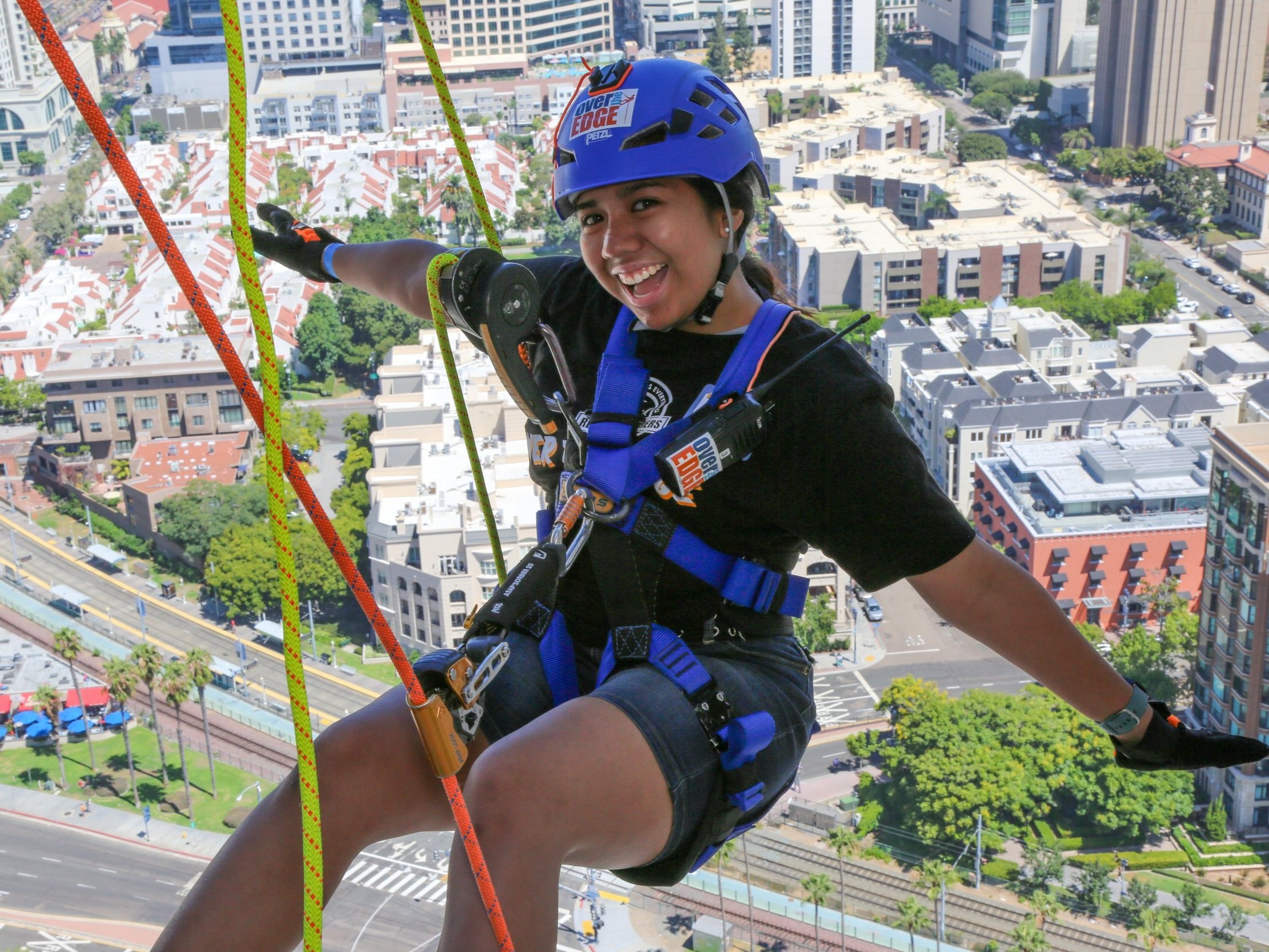 Girl rappelling down a downtown San Diego hotel during a community event, showcasing adventure activities.
