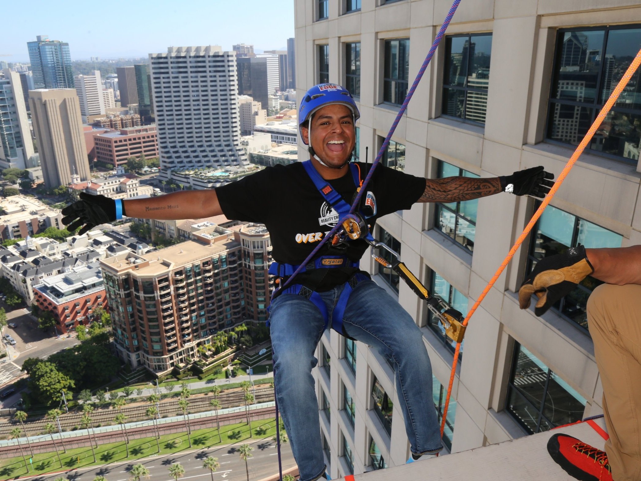 Man with a big smile participating in a rappelling event in San Diego, enjoying an outdoor adventure activity.
