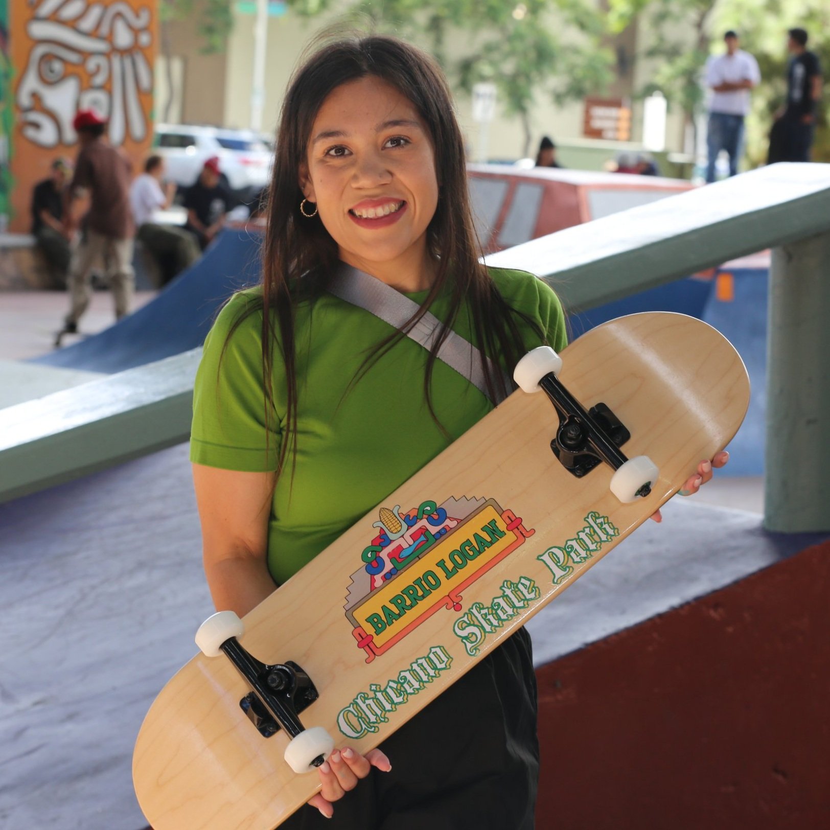 Girl posing with skateboard at Chicano Park Skatepark in San Diego, celebrating local skate culture and community space.
