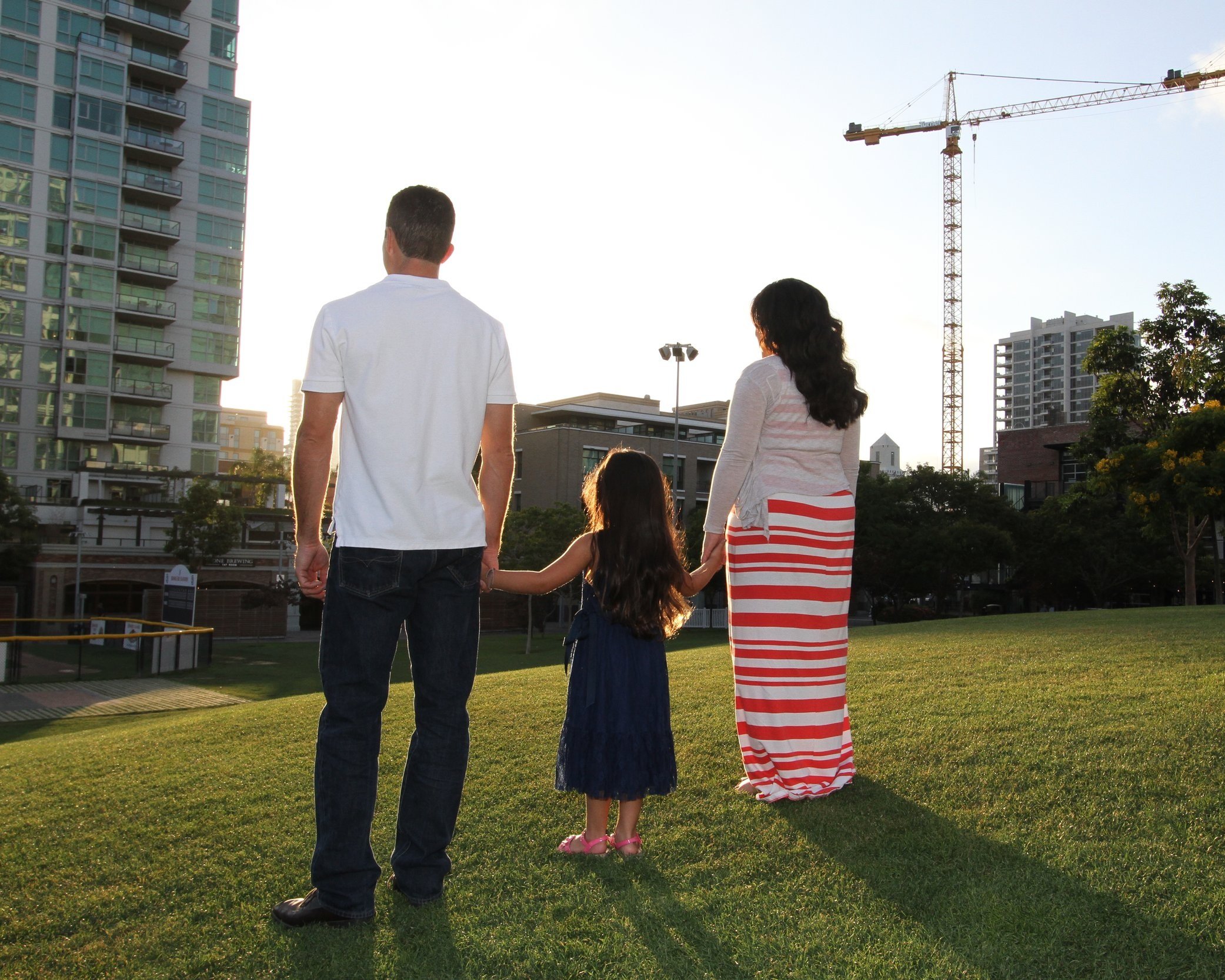 Parents holding their daughter's hands during a family photoshoot at Petco Park in San Diego, highlighting family love and togetherness.