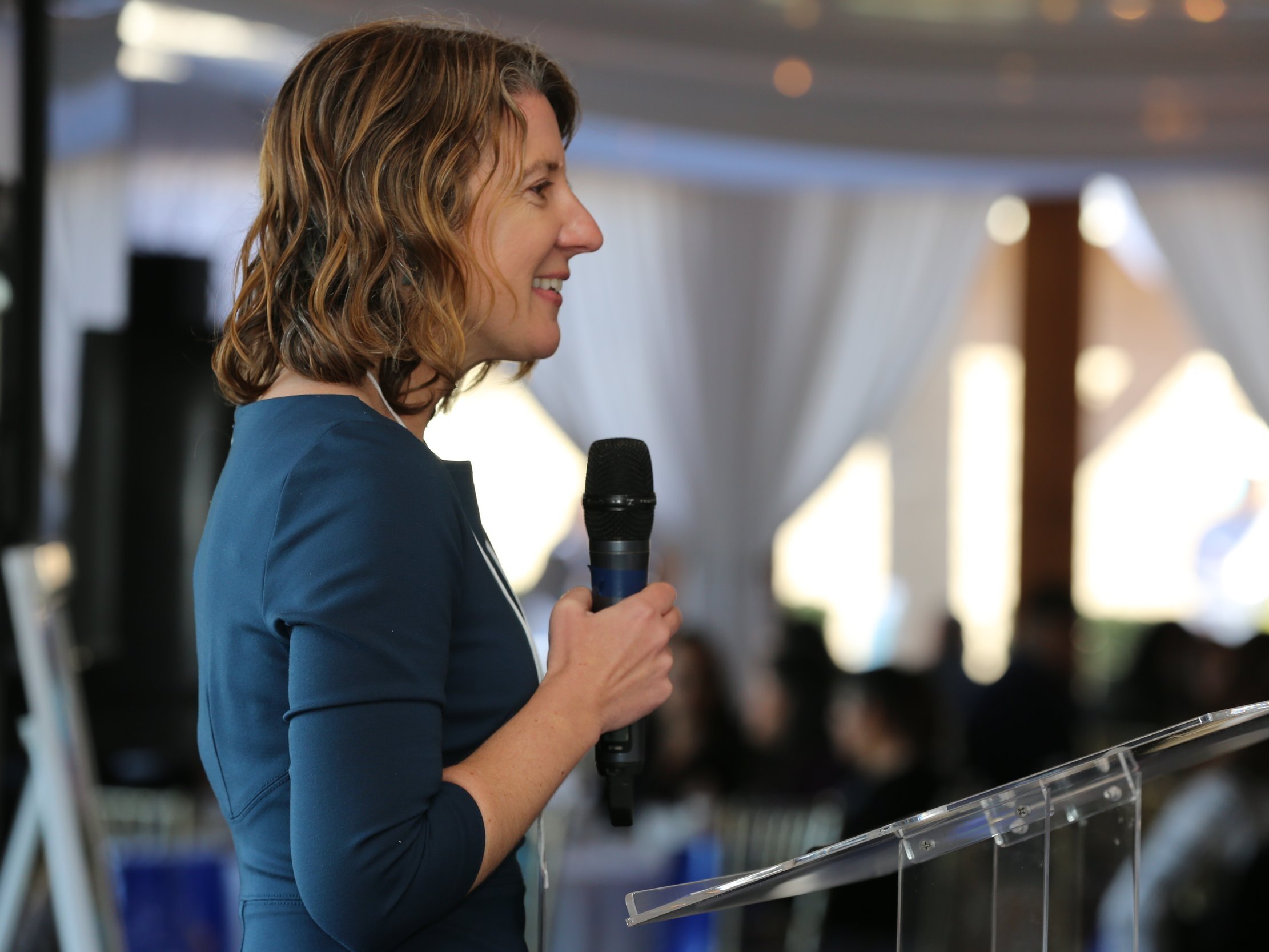 Woman delivering a speech at a professional corporate event in San Diego, engaging the audience.