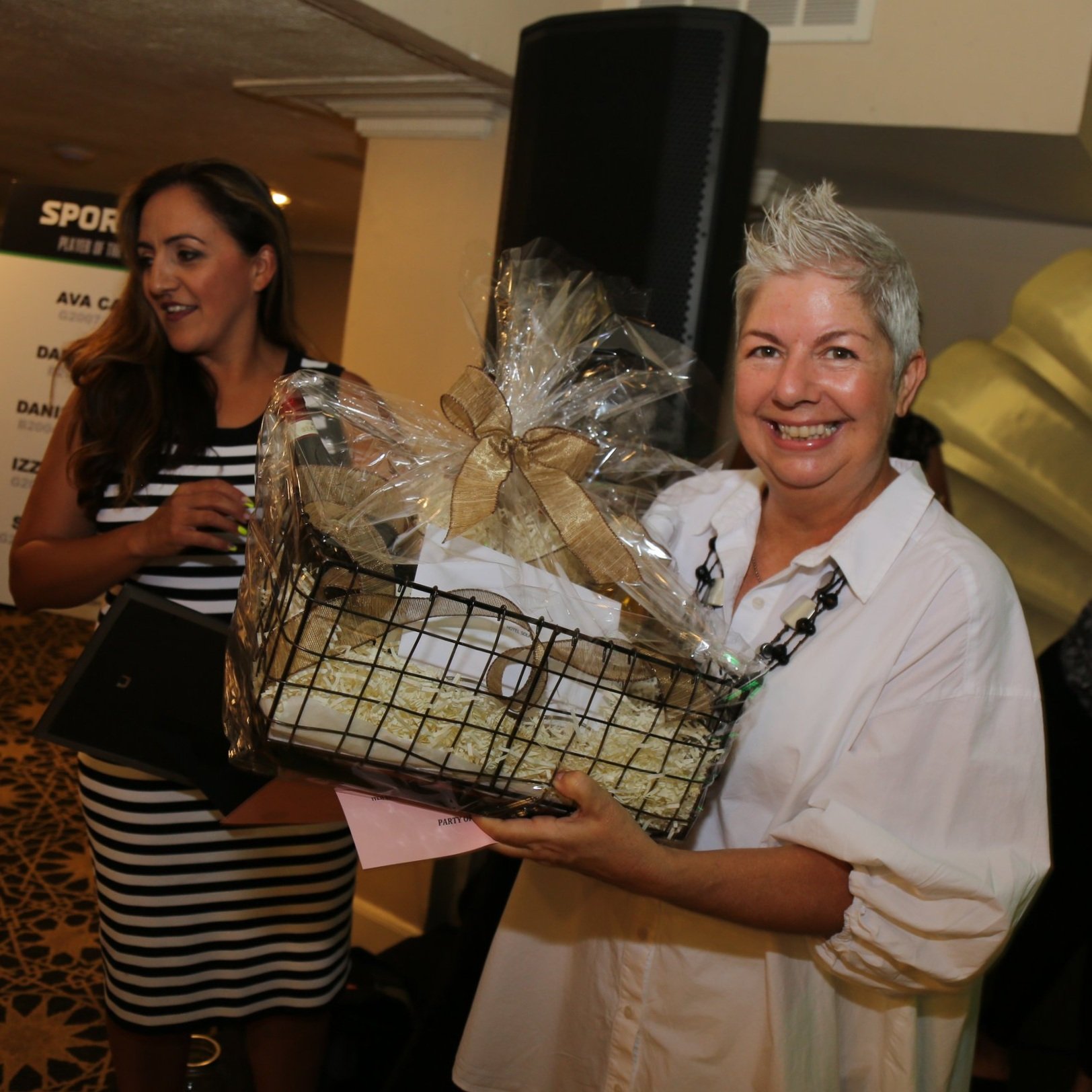 Woman receiving a gift basket at a community celebration held at the Lafayette Hotel in San Diego.