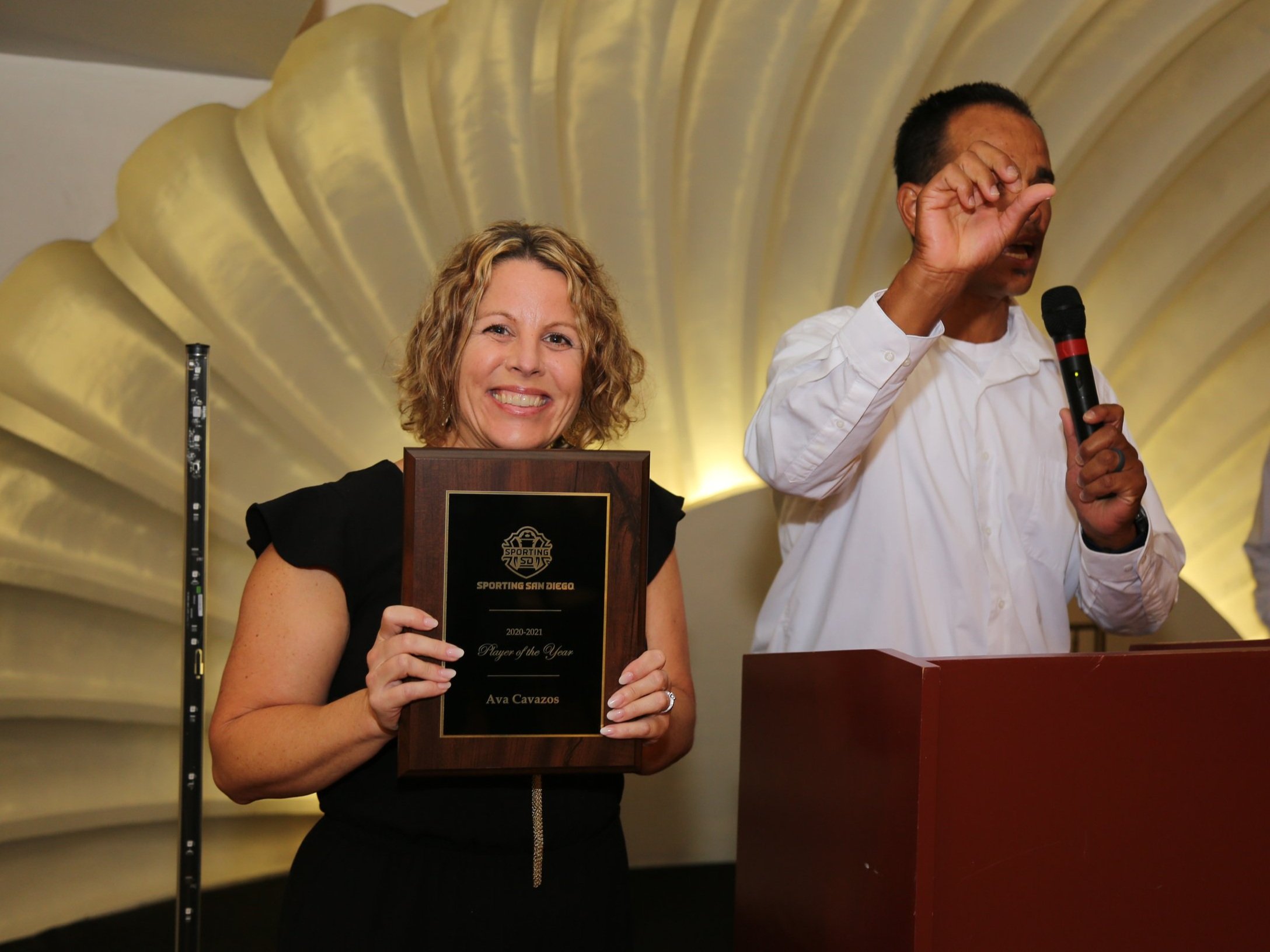 Woman presenting or displaying a plaque award during a recognition ceremony at the Lafayette Hotel in San Diego.