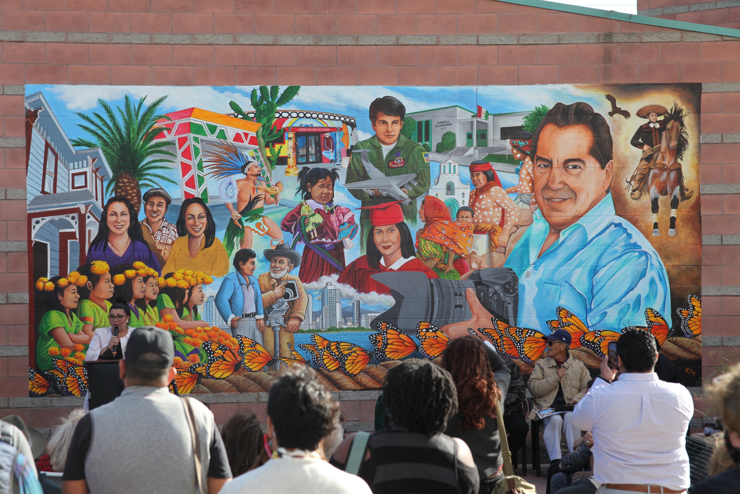 Crowd gathering around and viewing a mural in National City, celebrating local community art in San Diego.