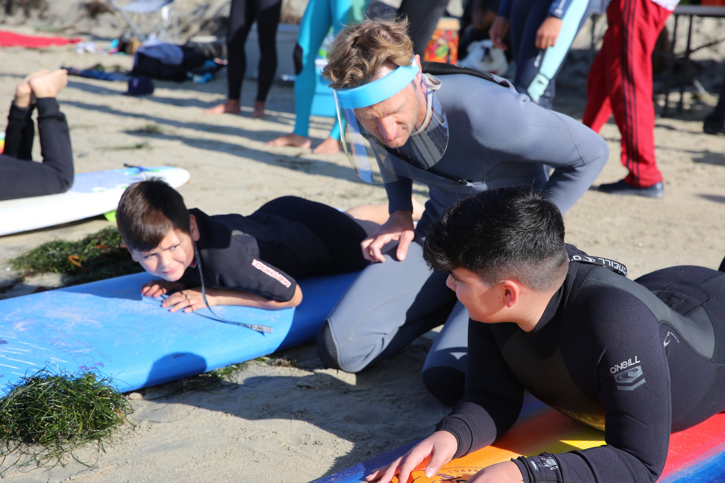 Instructor teaching kids the fundamentals of surfing during a community surfing event in San Diego.