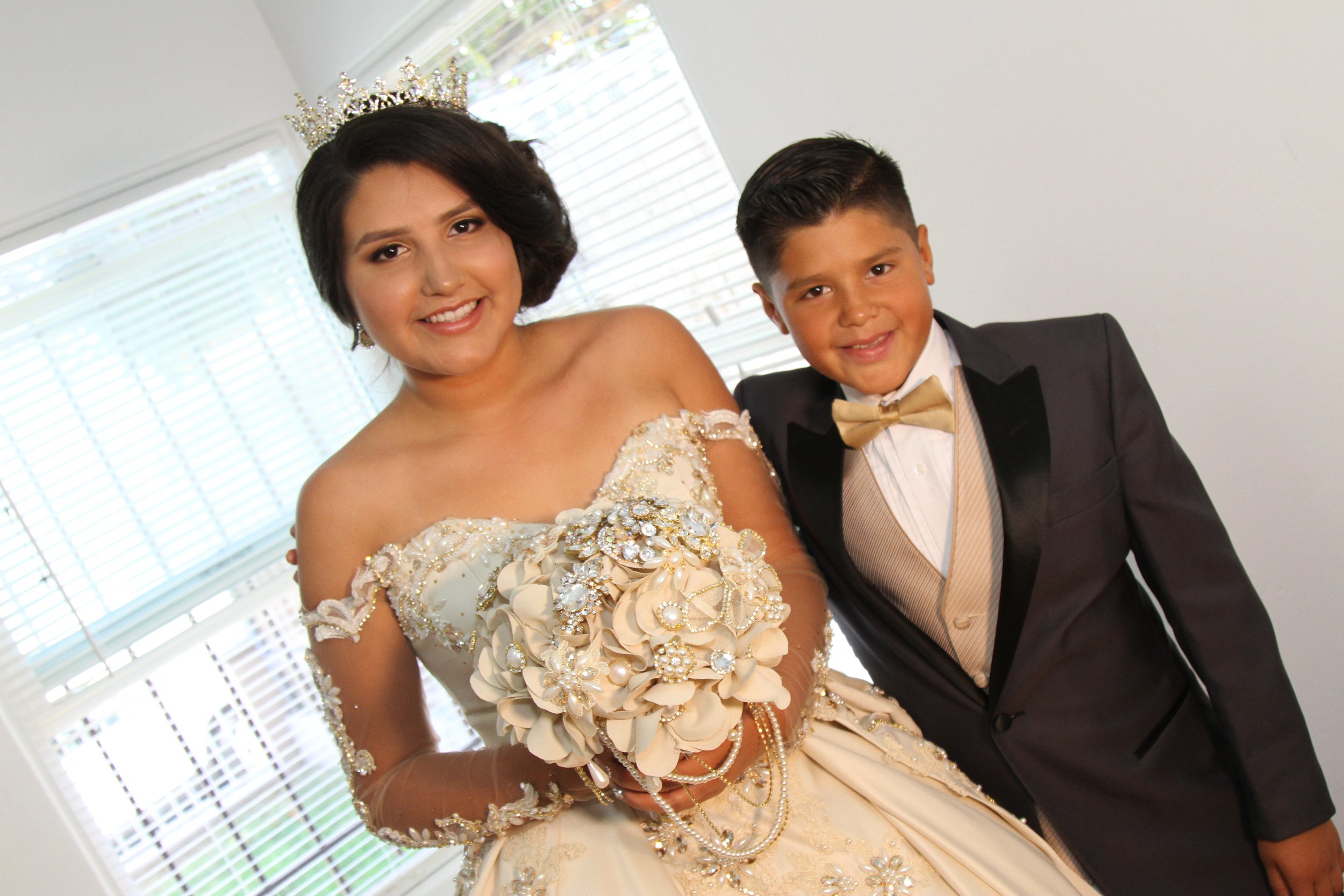 Sister and brother dressed in formal attire for a Quinceañera celebration, emphasizing family tradition and cultural pride.