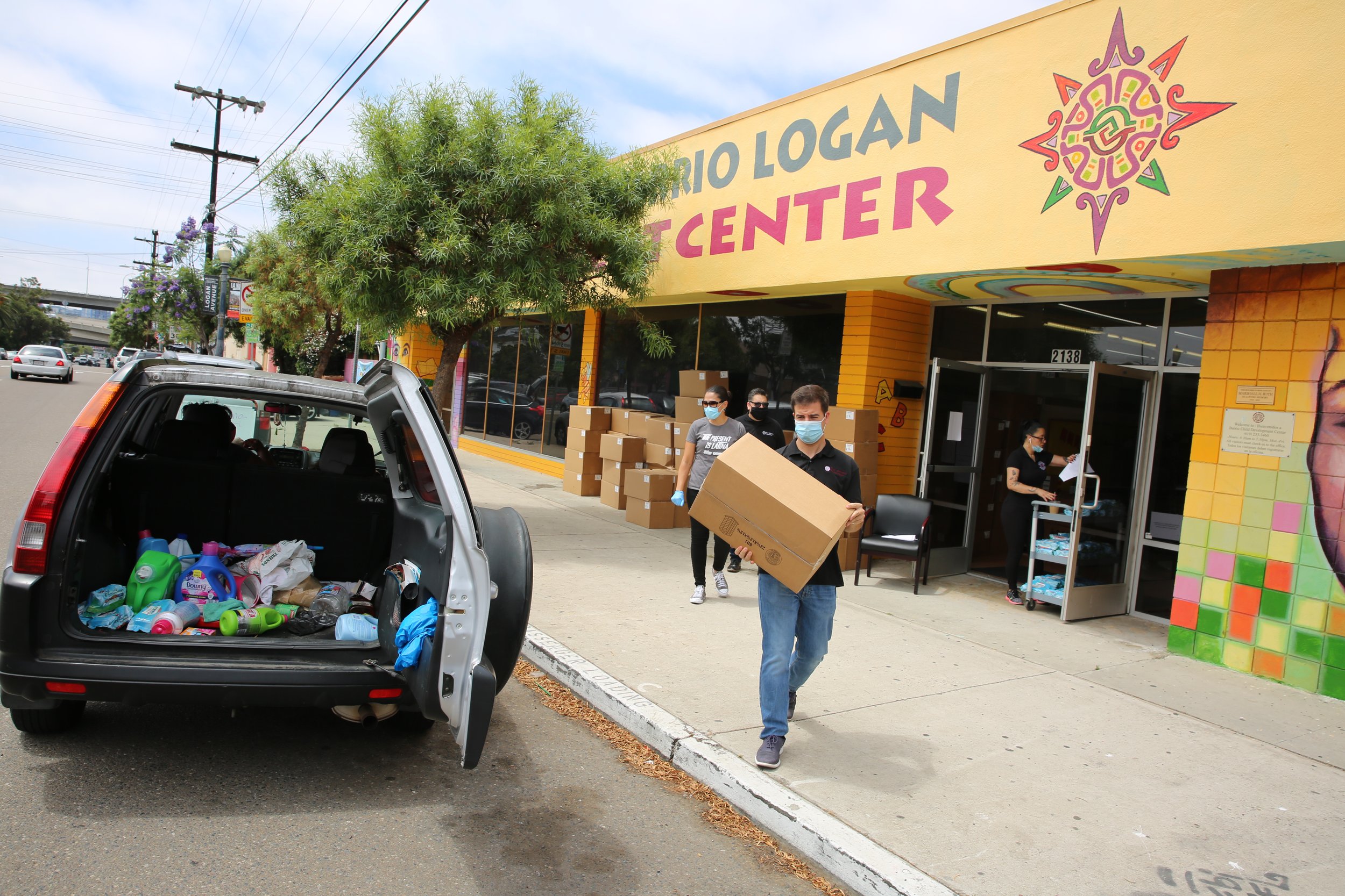 Person loading donations into a vehicle during a community support event in Barrio Logan, San Diego.