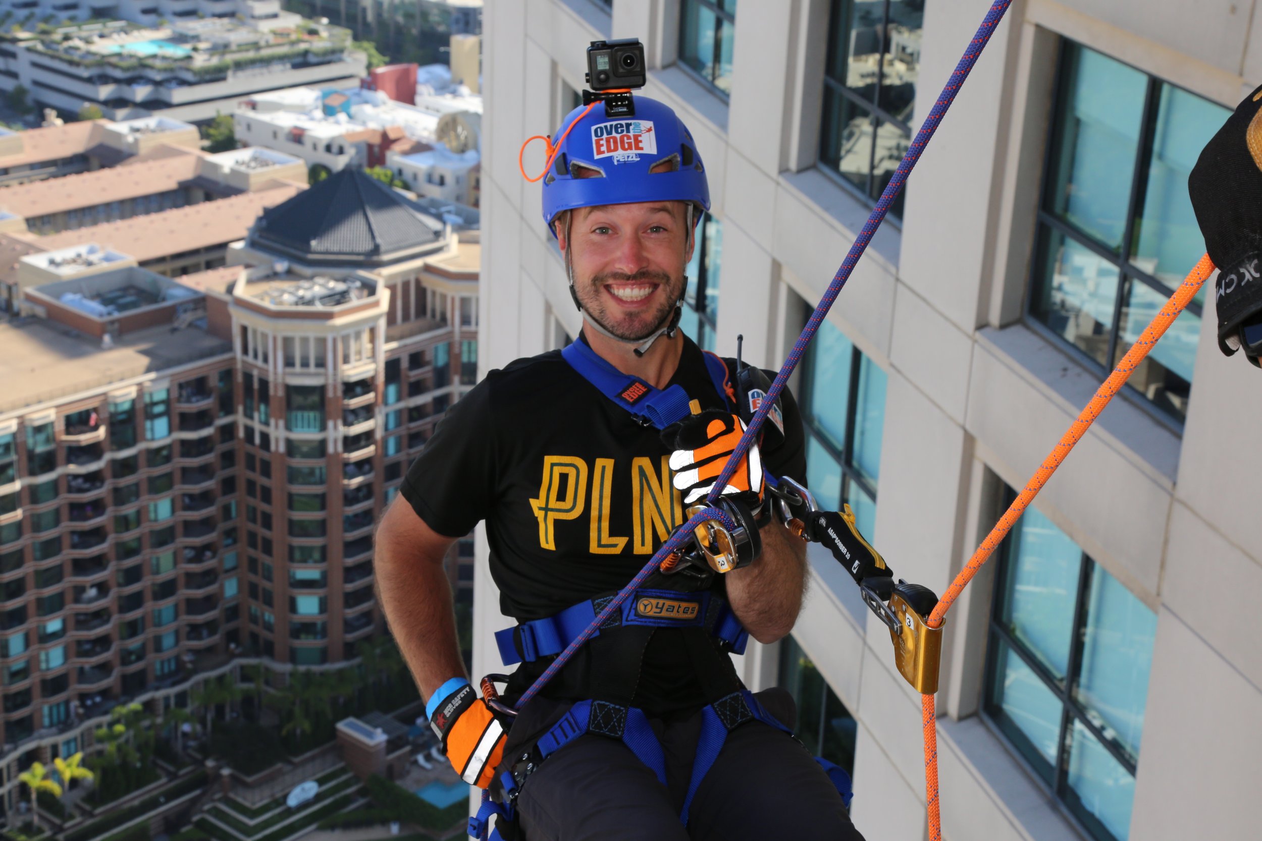 Man rappelling down a hotel during an event in downtown San Diego, showcasing adventure activities.