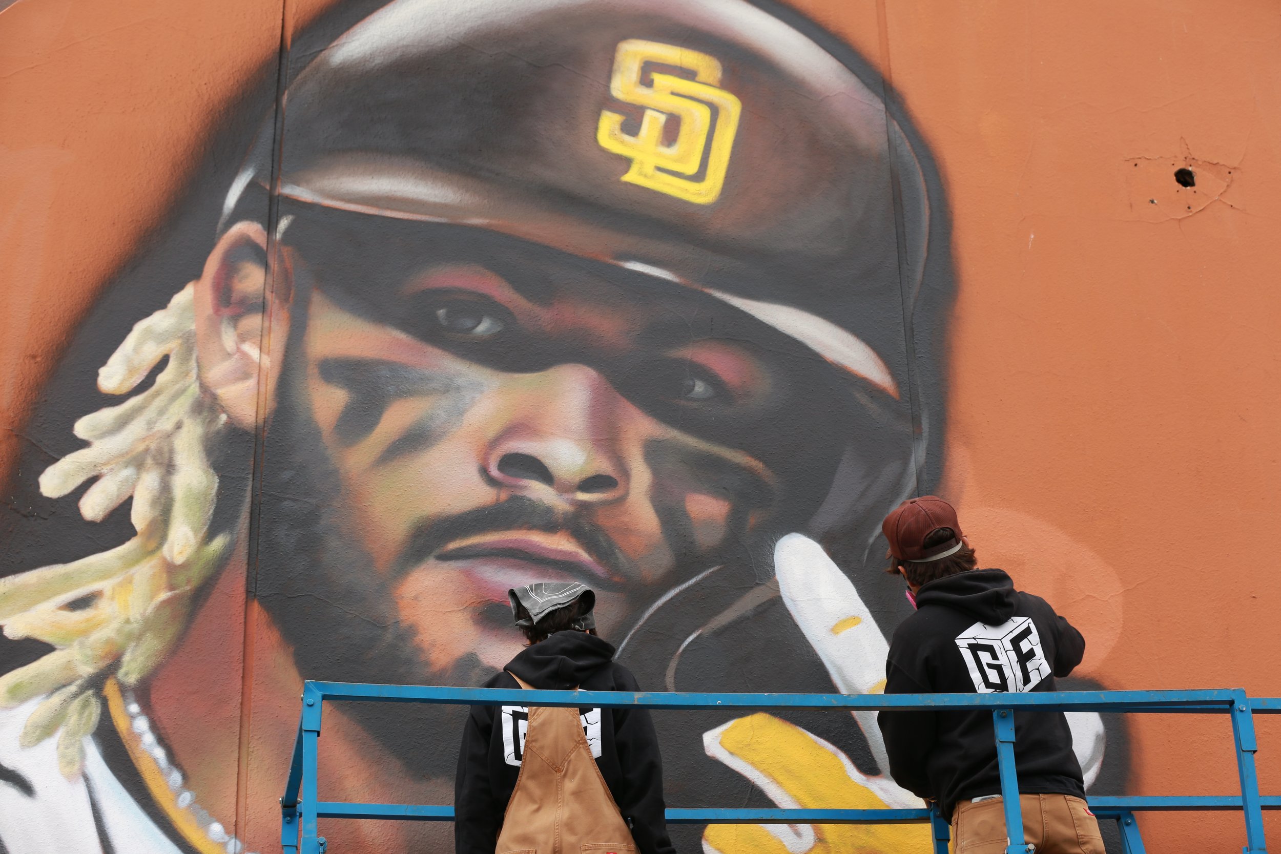 Artists collaboratively painting the San Diego Padres mural, showcasing local artwork honoring team spirit and community pride.