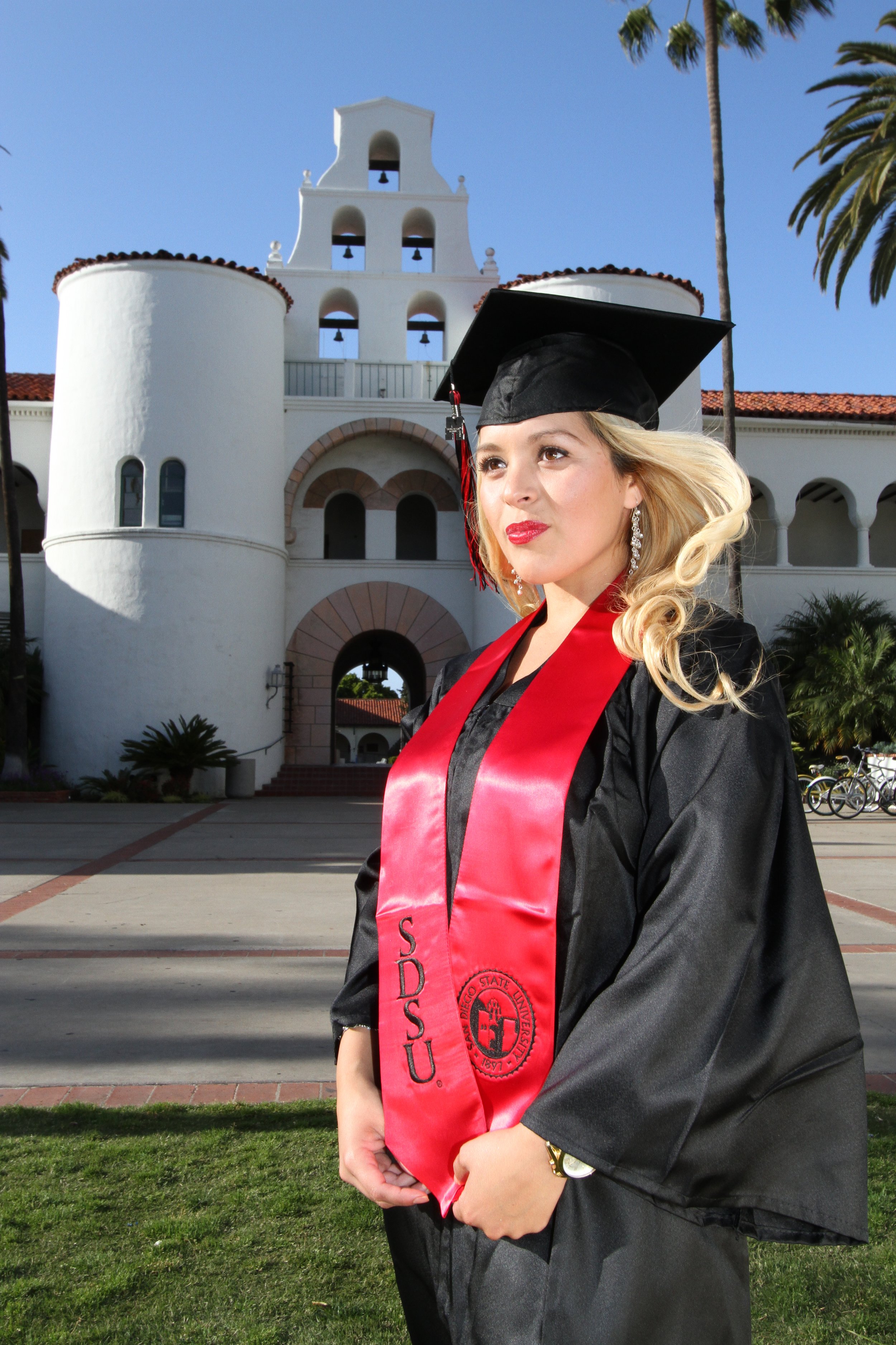 San Diego State University graduate in cap and gown posing on campus, celebrating graduation success in San Diego.