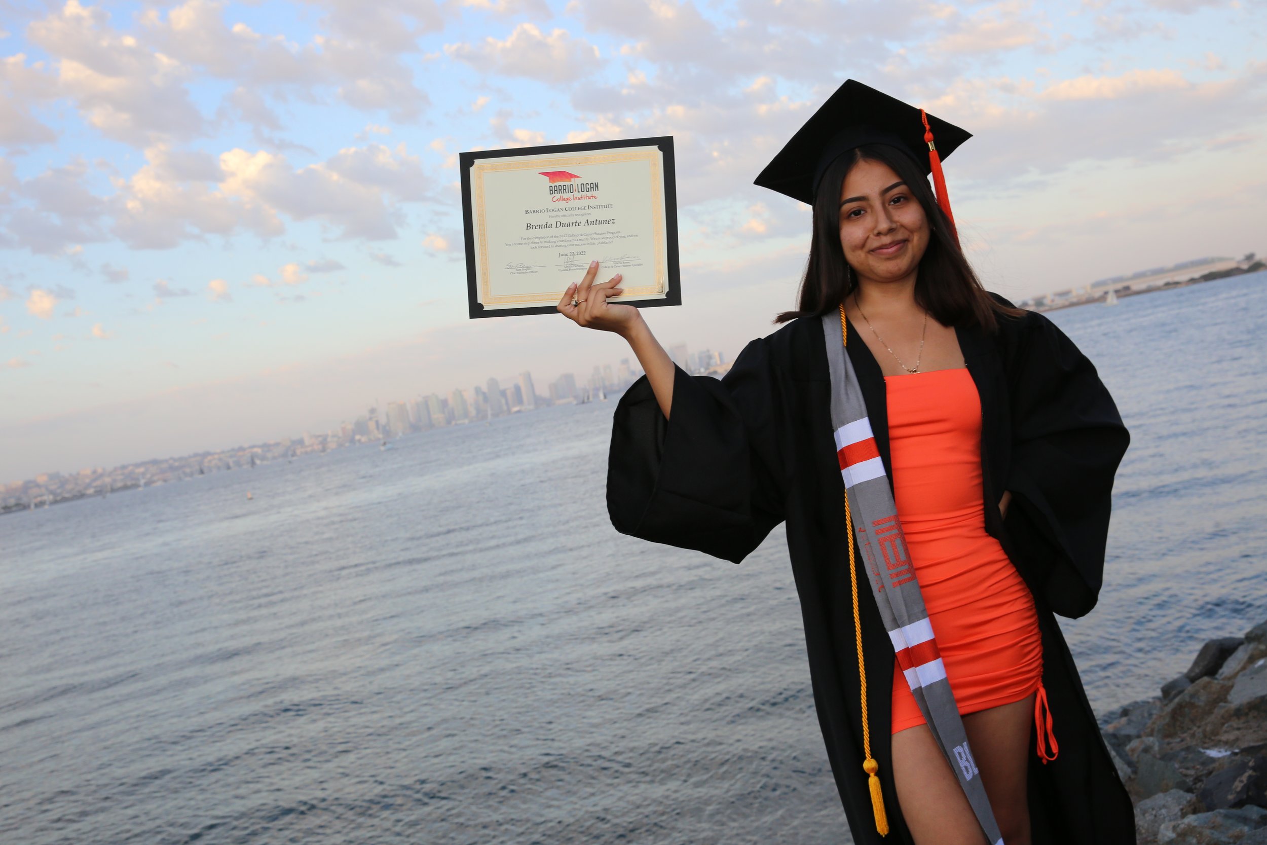 Graduate proudly displaying degree at Barrio Logan College Institute graduation ceremony in San Diego.