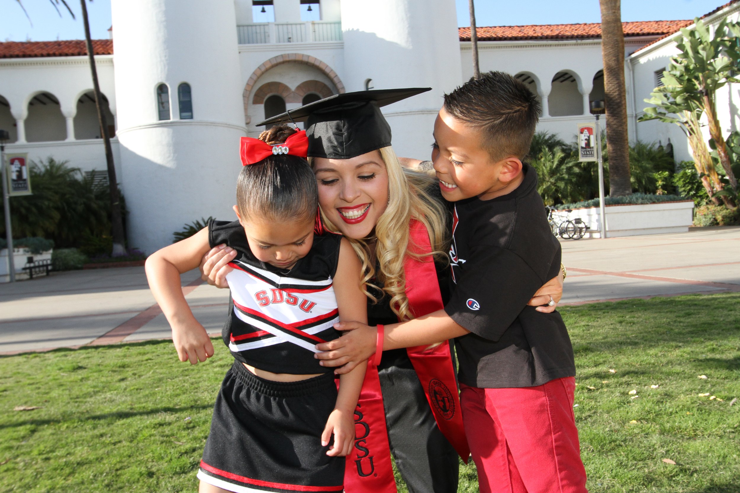 San Diego State University graduate sharing a special moment with children after graduation, celebrating academic achievement and family pride in San Diego.