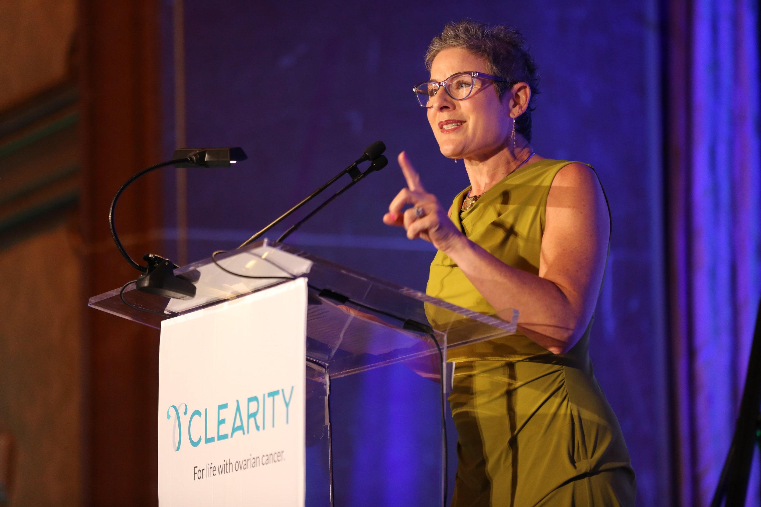 Woman delivering a speech at a corporate event for the Clearity Foundation in San Diego, highlighting community health initiatives.