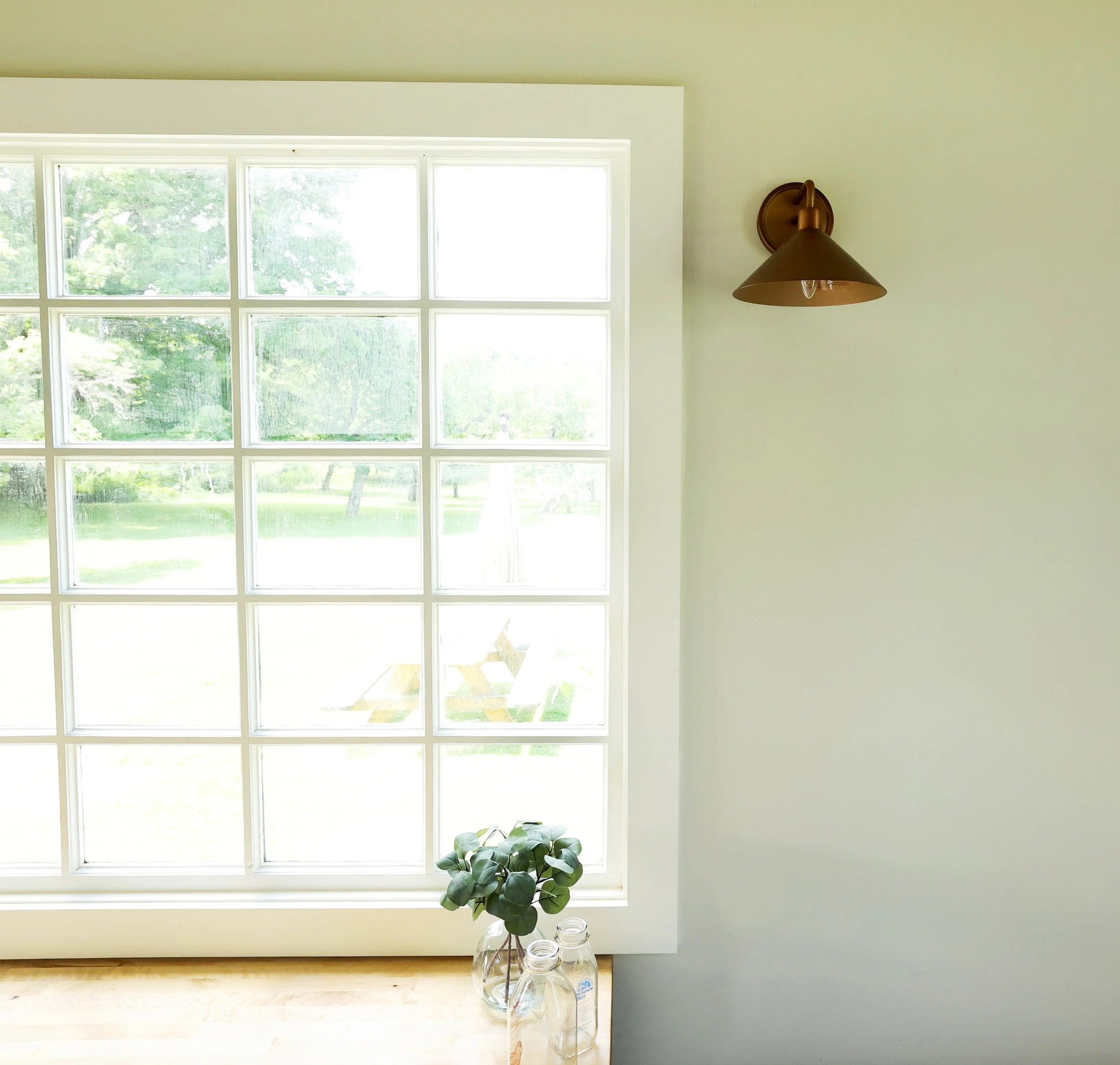 Wall sconce lighting beside farmhouse window in an Upper Valley mudroom renovation.