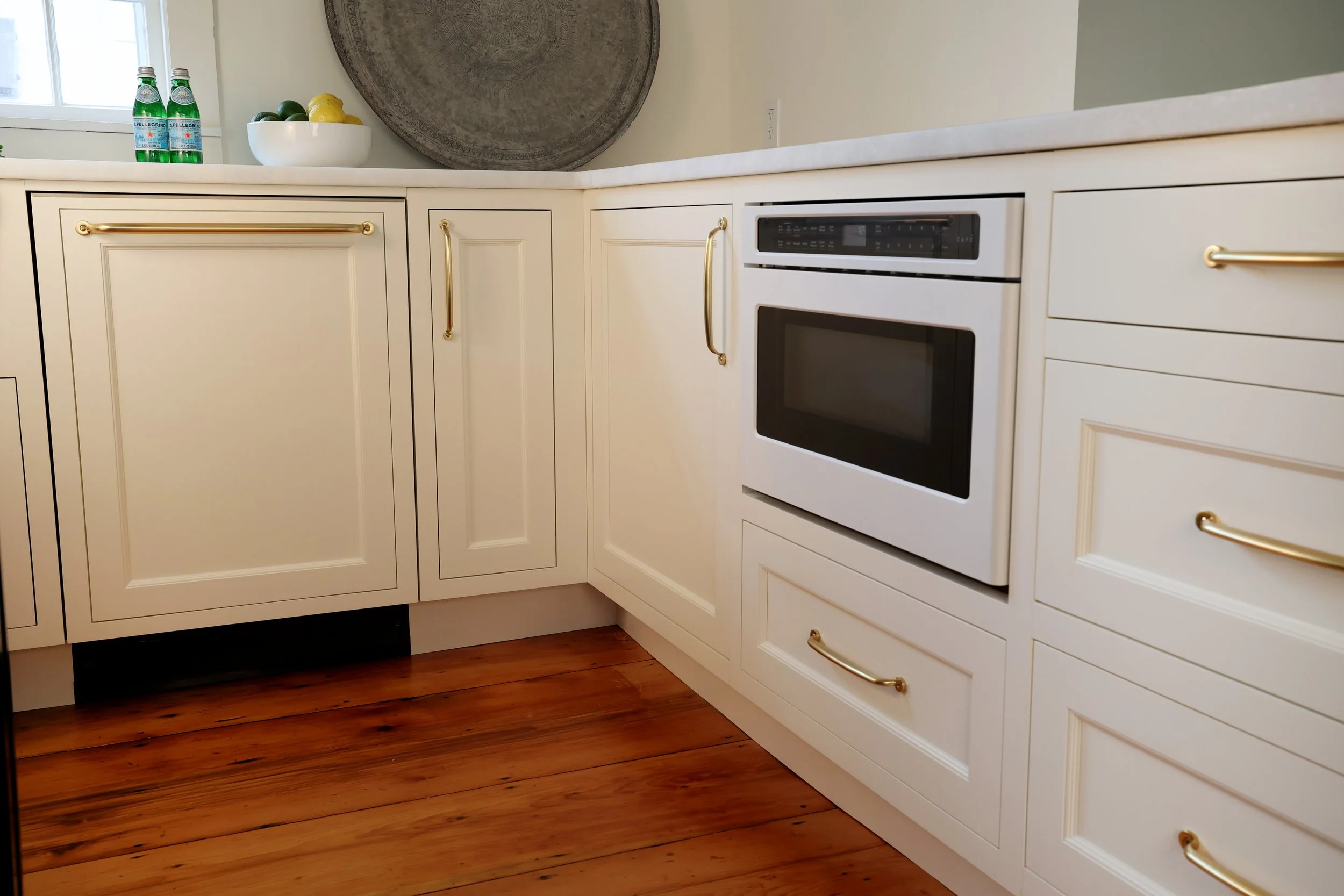 Integrated white Café drawer microwave built into custom cream cabinetry in a Vermont kitchen renovation.