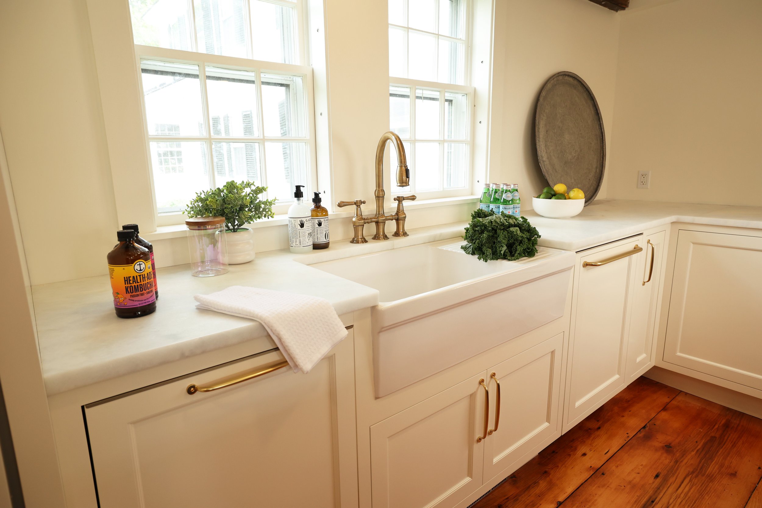 Farmhouse fire clay sink from Rejuvenation beneath double windows with brass faucet in a historic Vermont kitchen renovation.