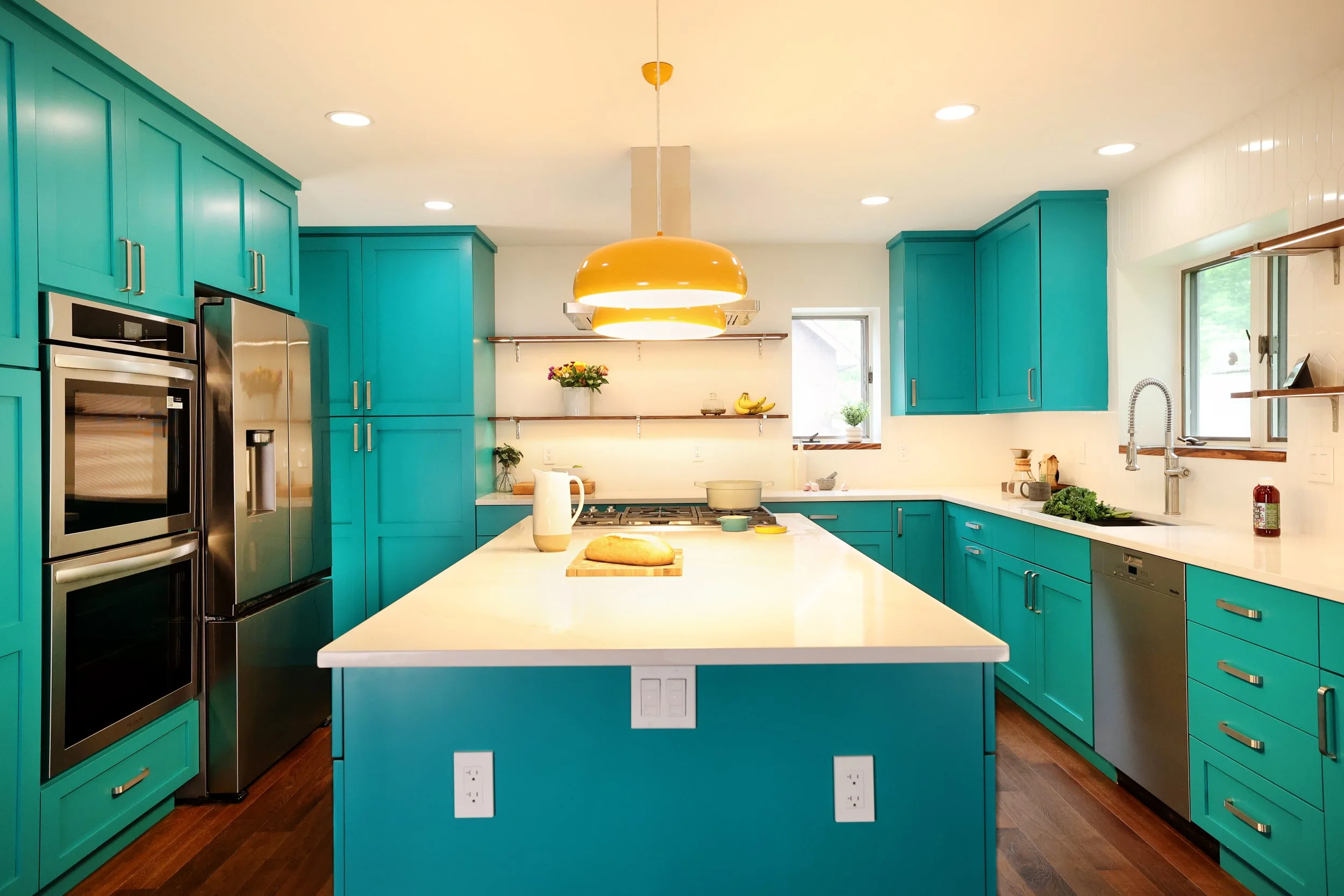 Midcentury kitchen layout with teal cabinets and wood flooring in a White River Junction Vermont home