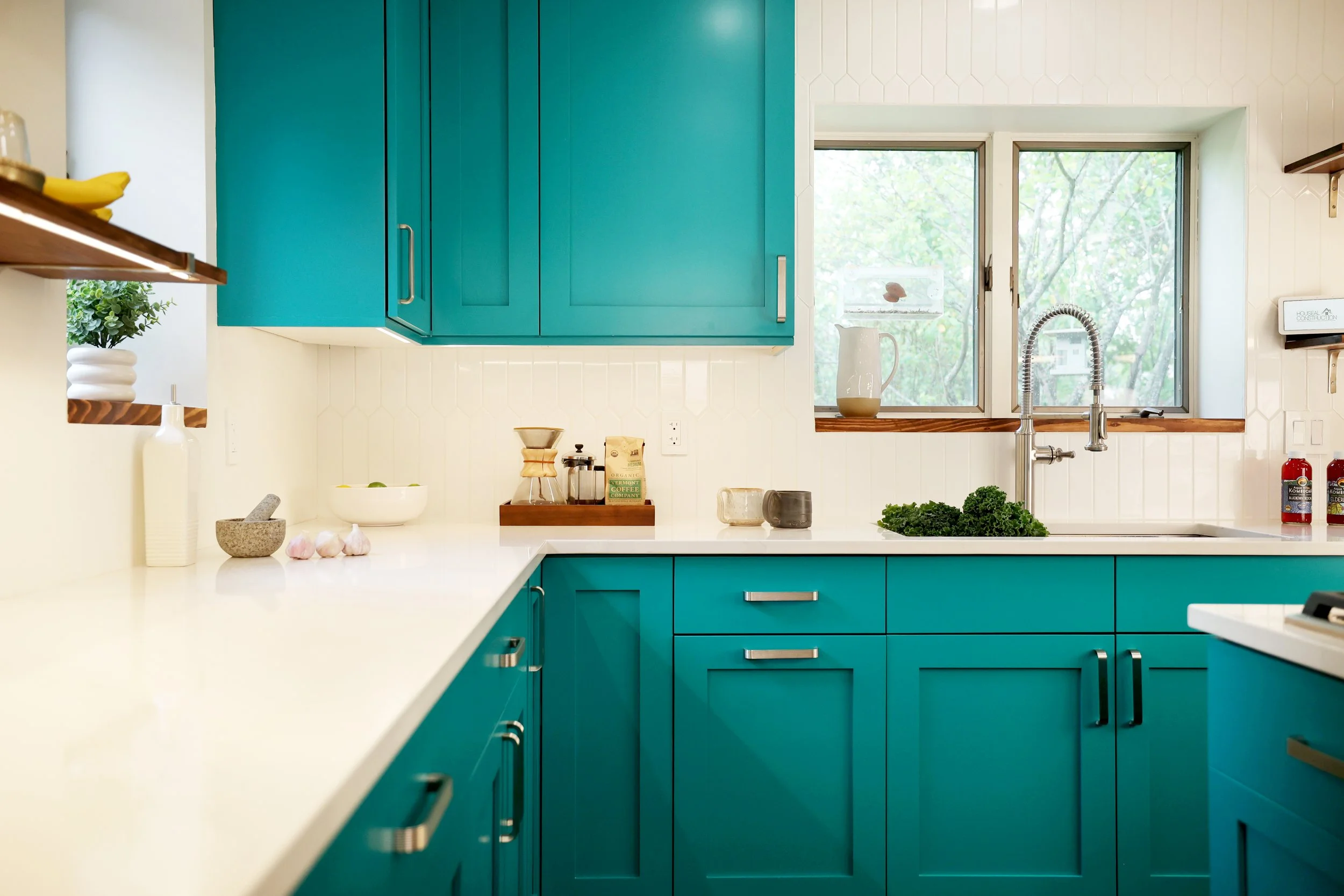 Kitchen renovation with teal cabinetry, white tile backsplash, quartz countertops, and modern fixtures in a bright New England kitchen.