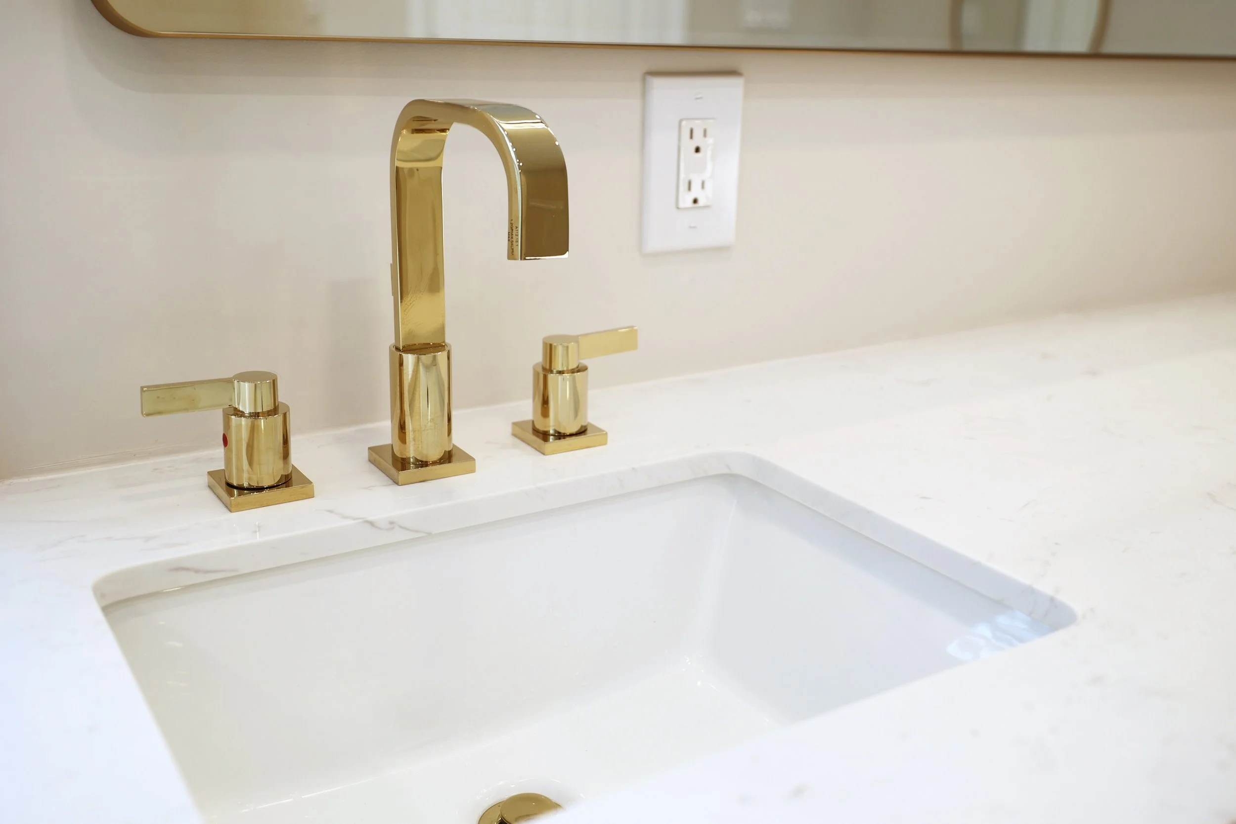 Polished brass faucet mounted on a bathroom vanity countertop in a Lebanon NH primary bath.